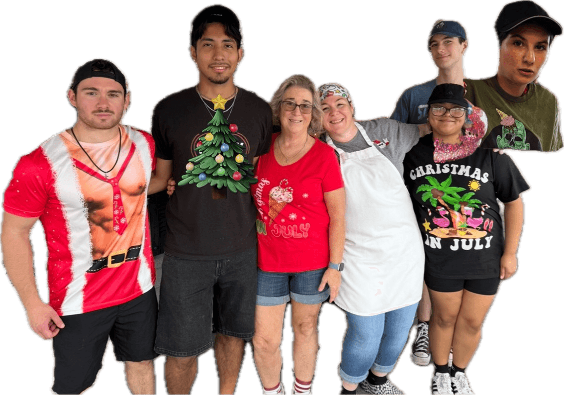 Group of seven people celebrating Christmas, some wearing holiday-themed clothing, standing together against a black background.