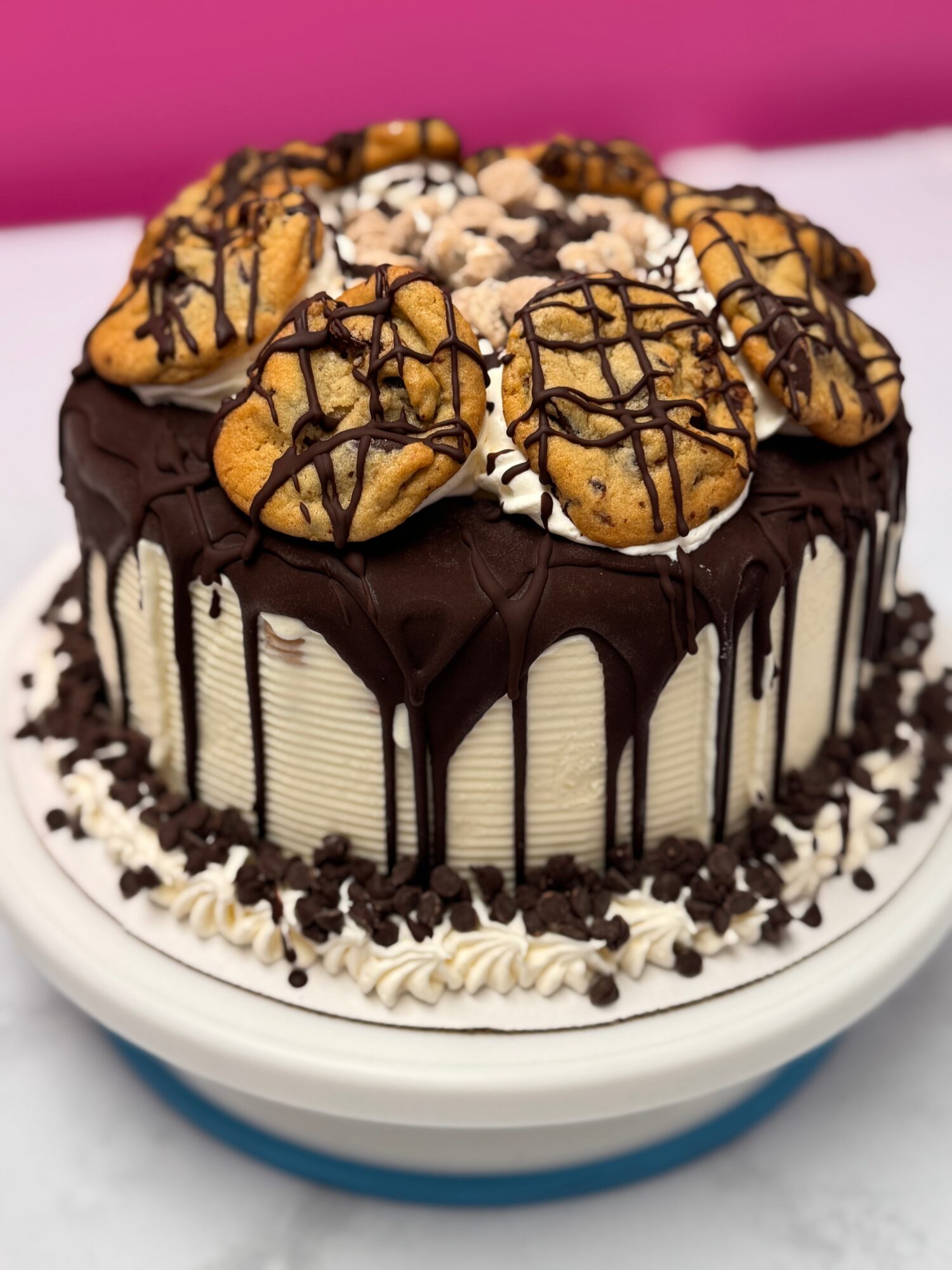 Cake with chocolate glaze, topped with cookies and chocolate drizzle, on a white and blue plate.