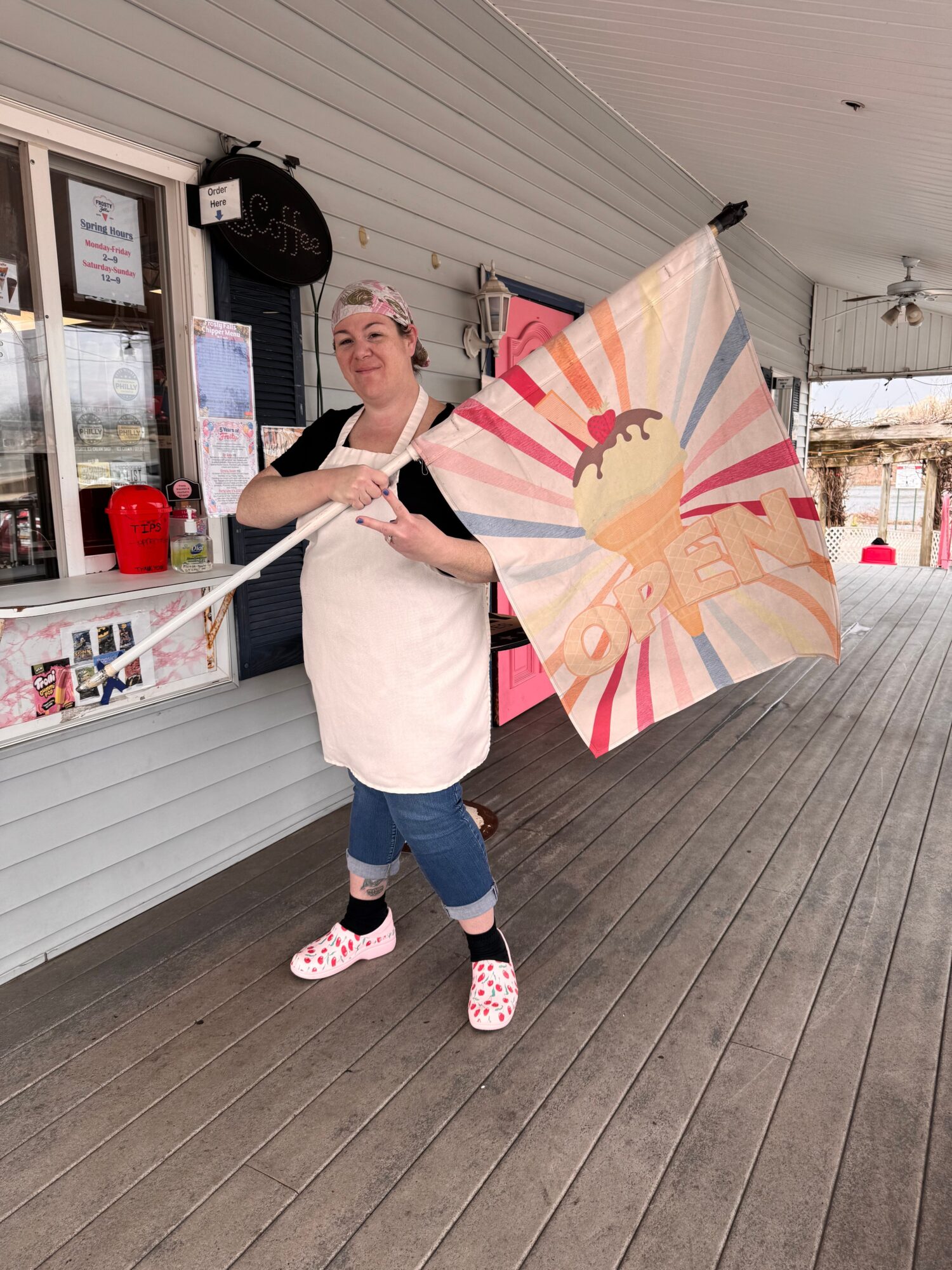 Person holding a colorful umbrella with a princess design, standing on a wooden deck outside a building.