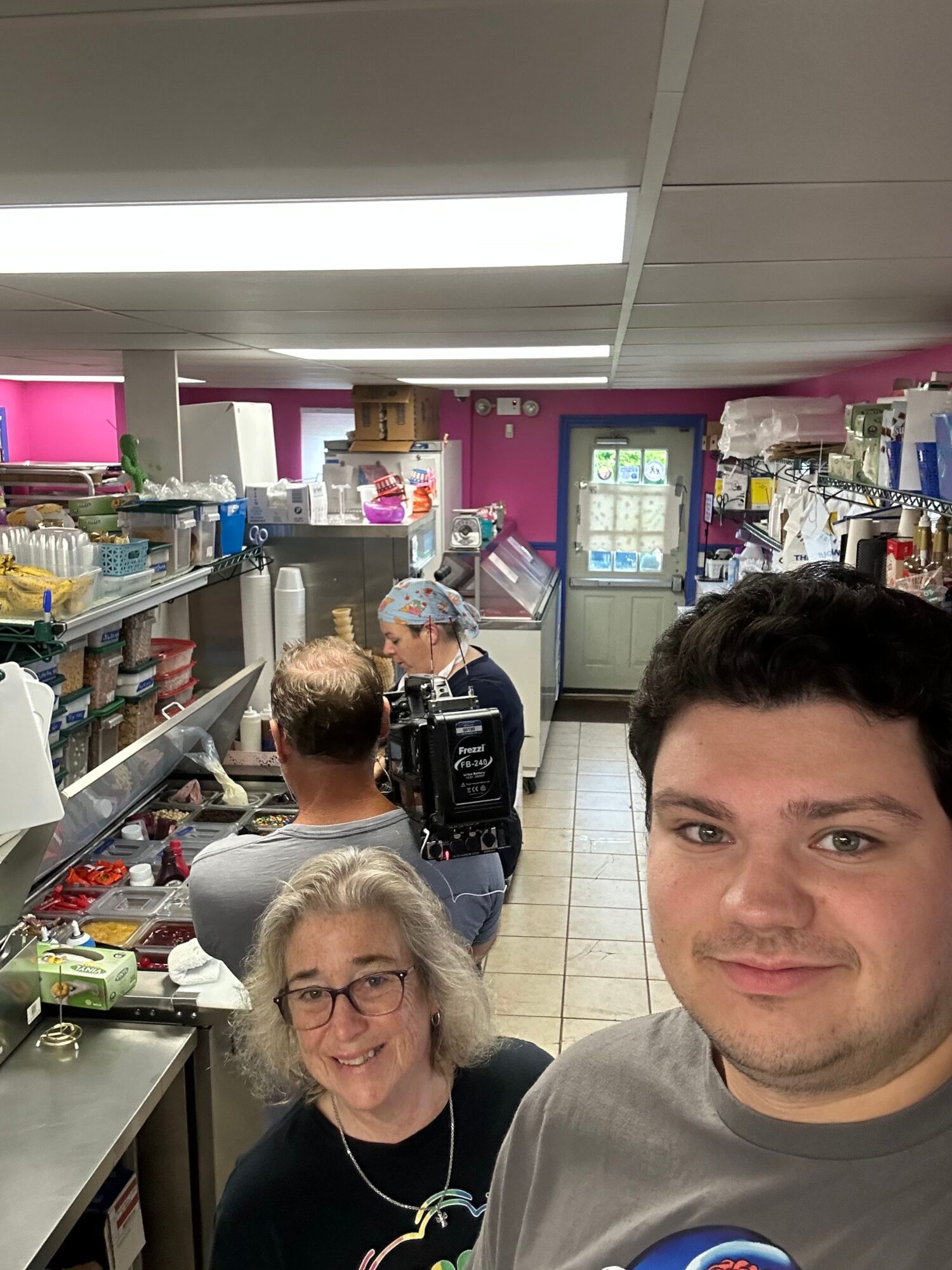 People shopping at a store checkout counter with various products and a cashier in the background.