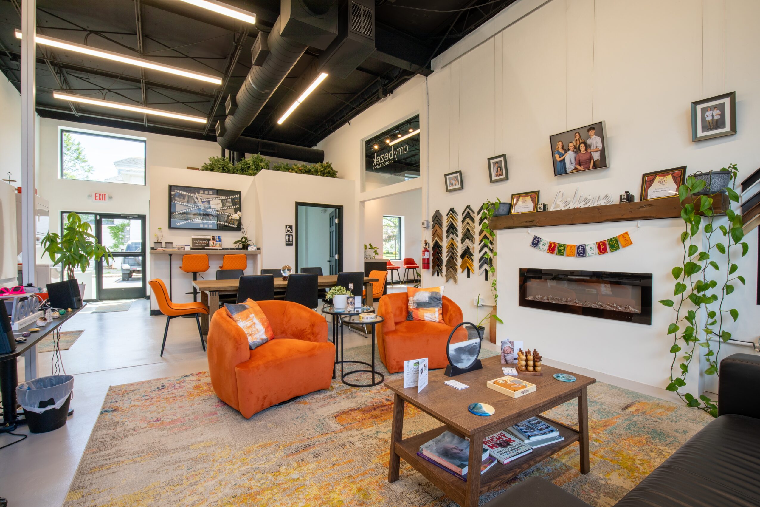 Modern living room with orange sofas, a wooden coffee table, wall decorations, and large windows letting in natural light.