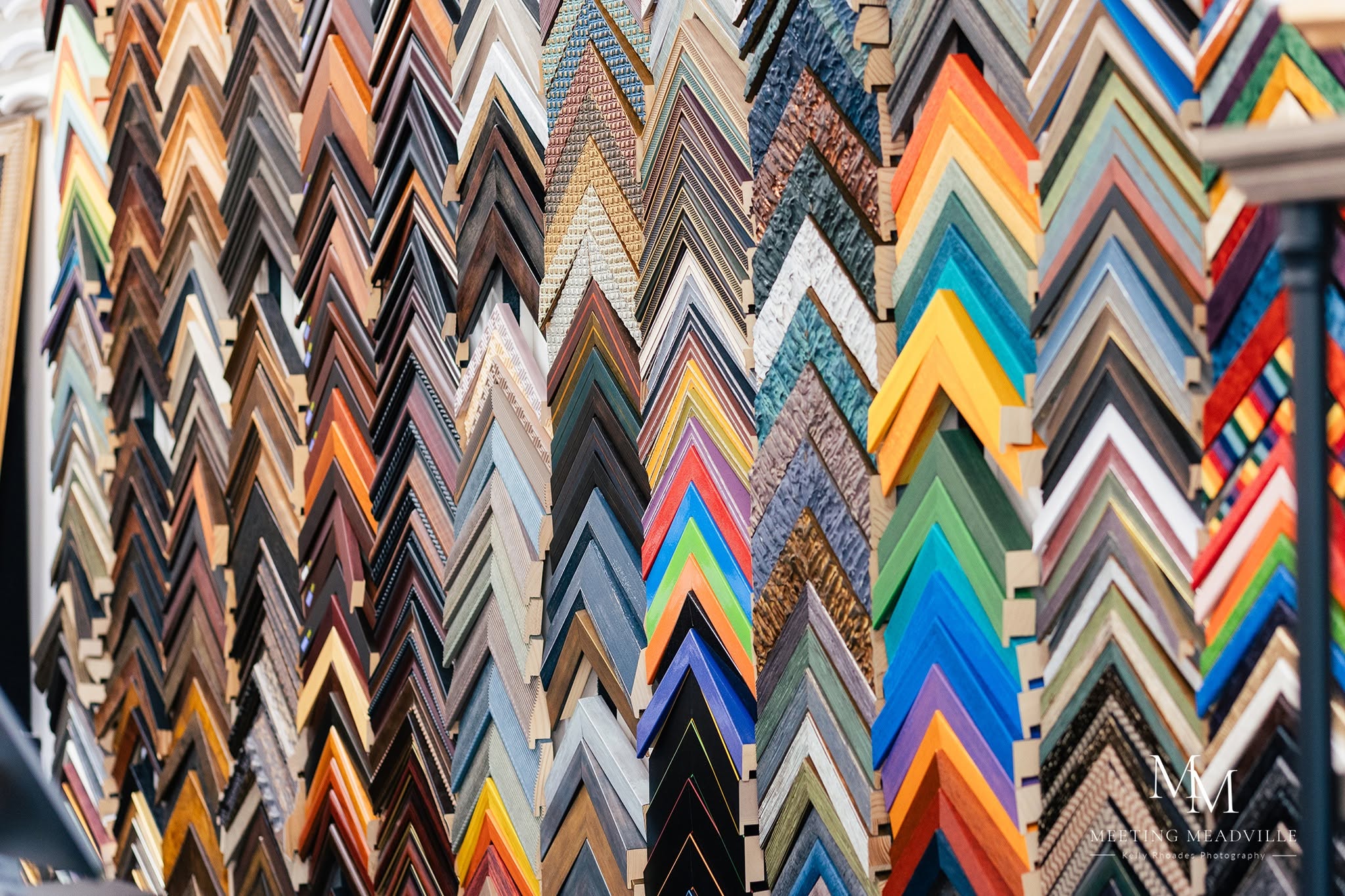 Display of various colorful and patterned picture frame samples arranged vertically in a store.