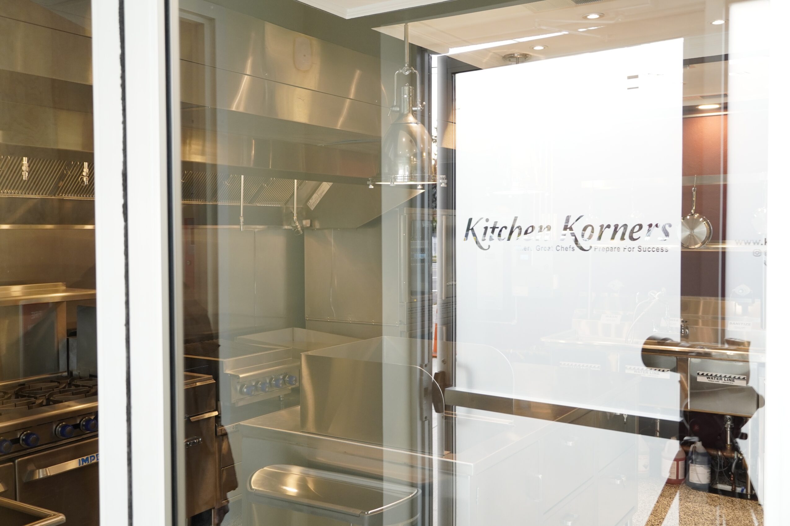 Glass door with a sign reading 'Kitchen Korner's' in a restaurant or cafe setting.