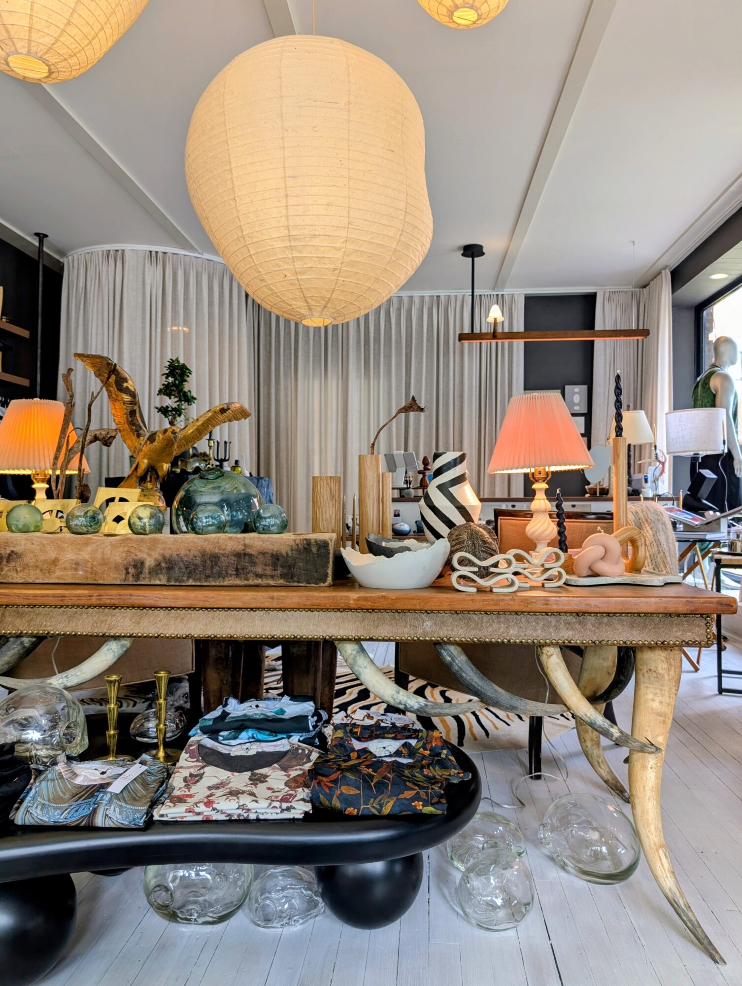 Interior room with hanging paper lantern, wooden table with decorative items, lamps, and curtains, in a modern style.