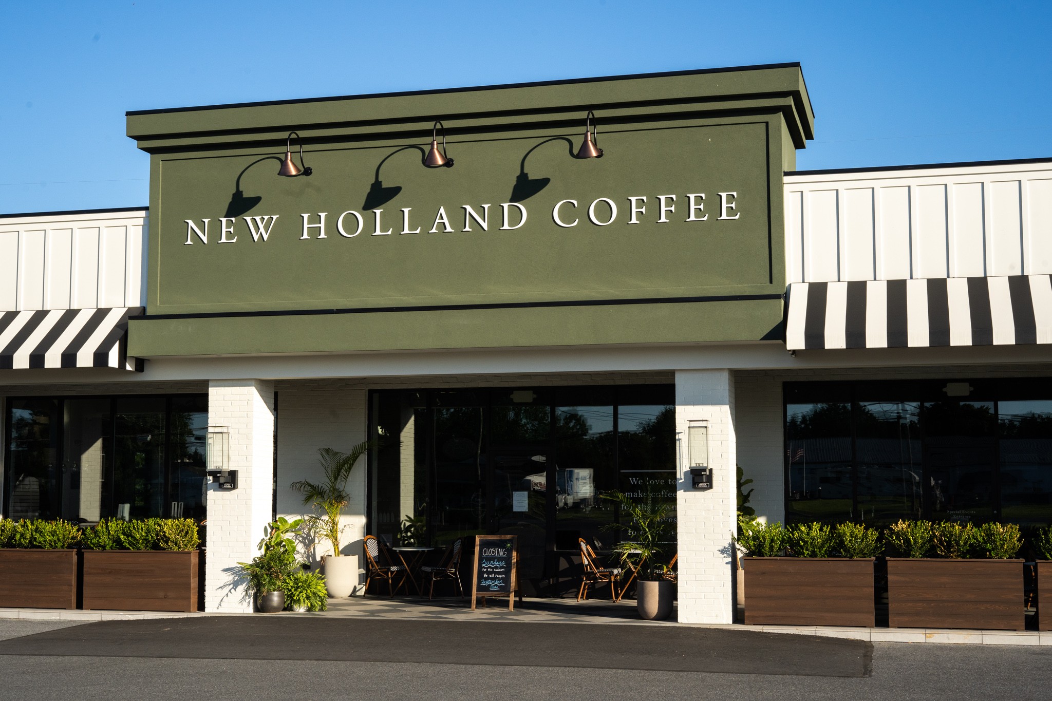 Facade of a coffee shop with a green sign reading 'New Holland Coffee' and outdoor seating area.