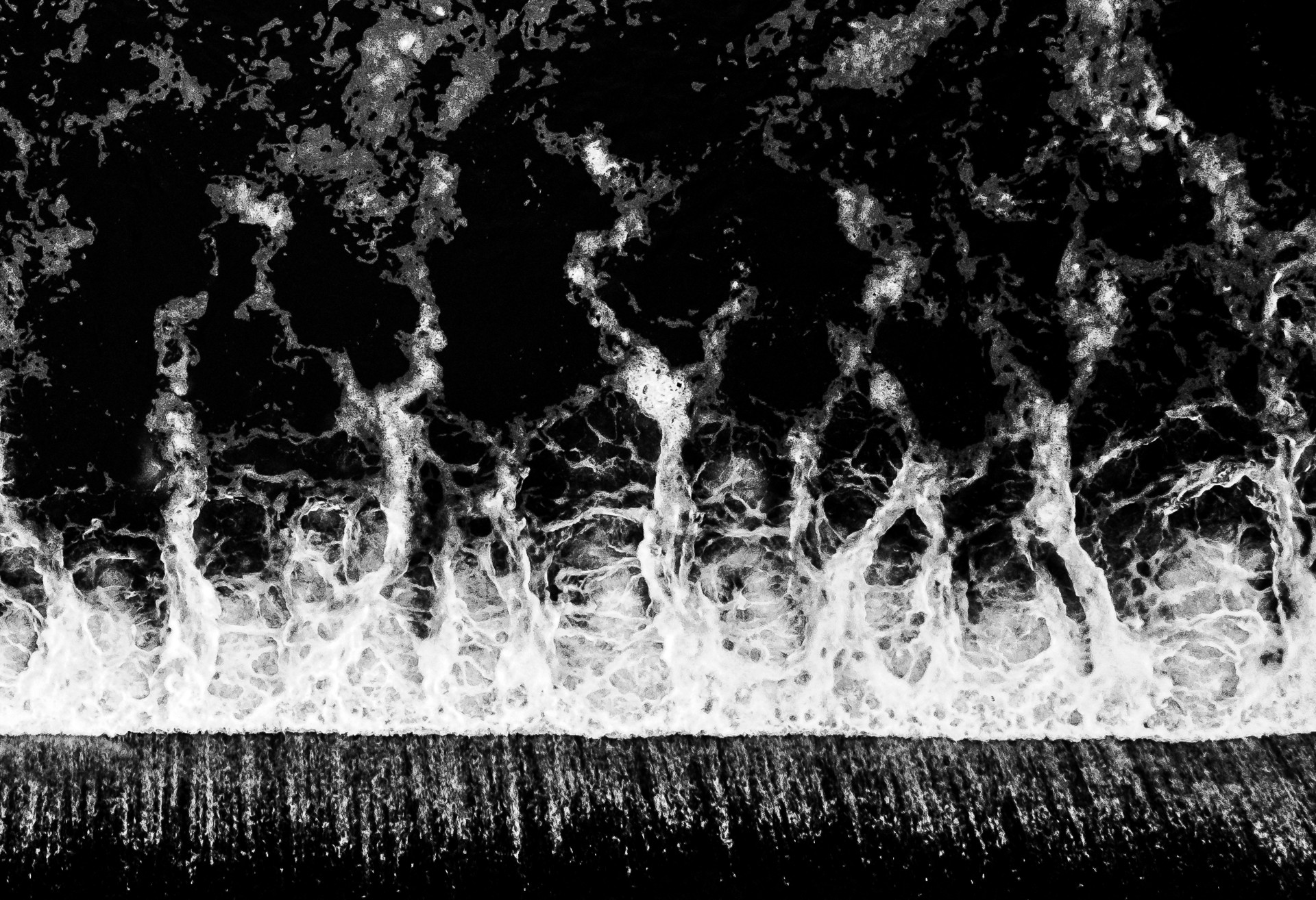 Abstract black and white pattern resembling water or flames, with a horizontal line at the bottom.