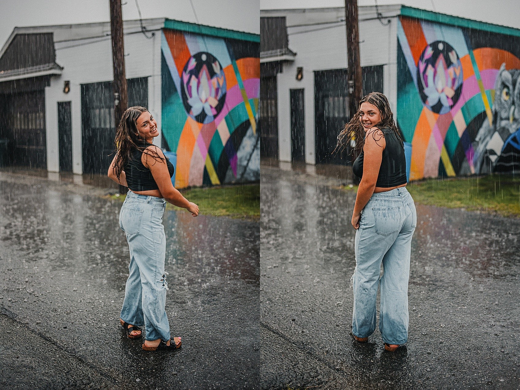 Two women standing on a rainy street with a colorful mural behind them, smiling and looking at the camera.