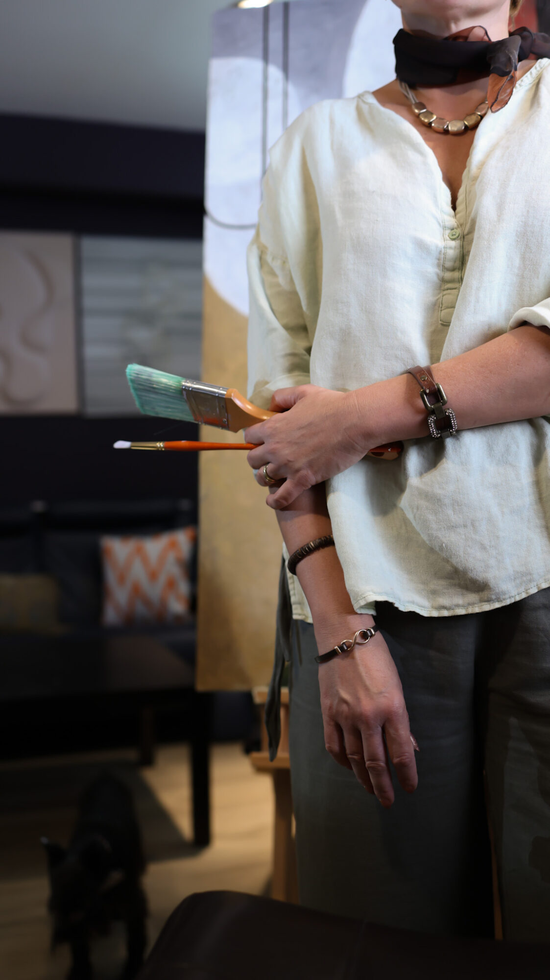 Person holding a smartphone, wearing a white shirt, watch, and bracelets, with a blurred background.