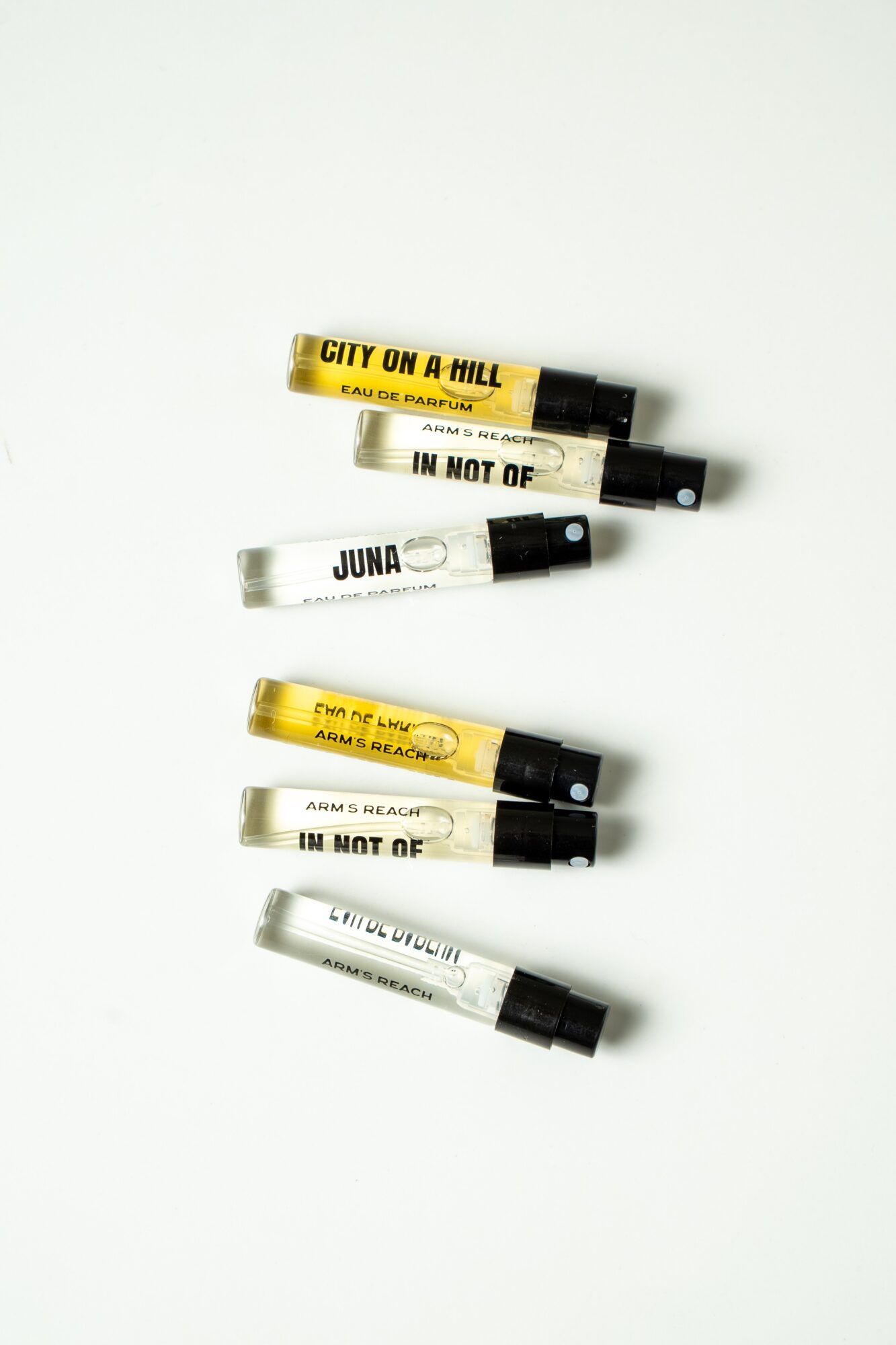 Five small tubes with black caps, some with yellow and white labels, arranged vertically on a white background.