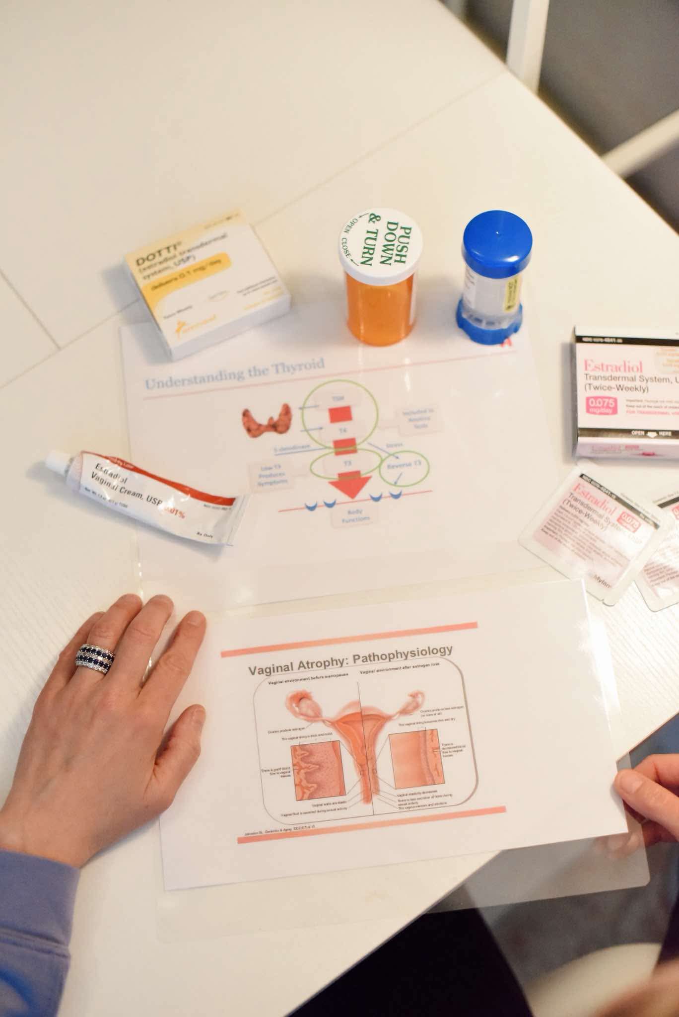 Medical items and informational papers on a white table, with a person's hand visible on the left side.