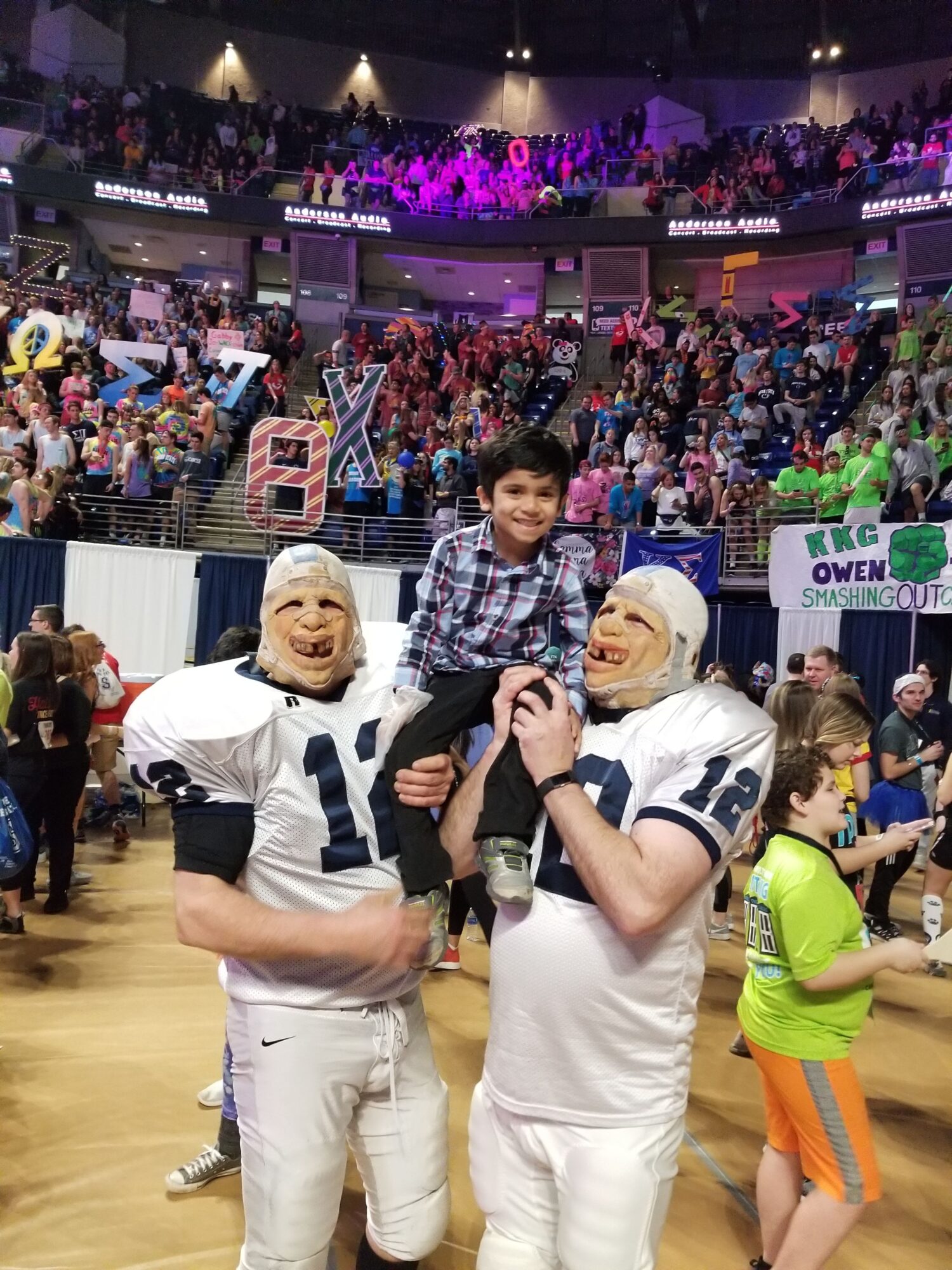 Two women dressed as police officers posing with a person in a costume, in a lively indoor event with many attendees.
