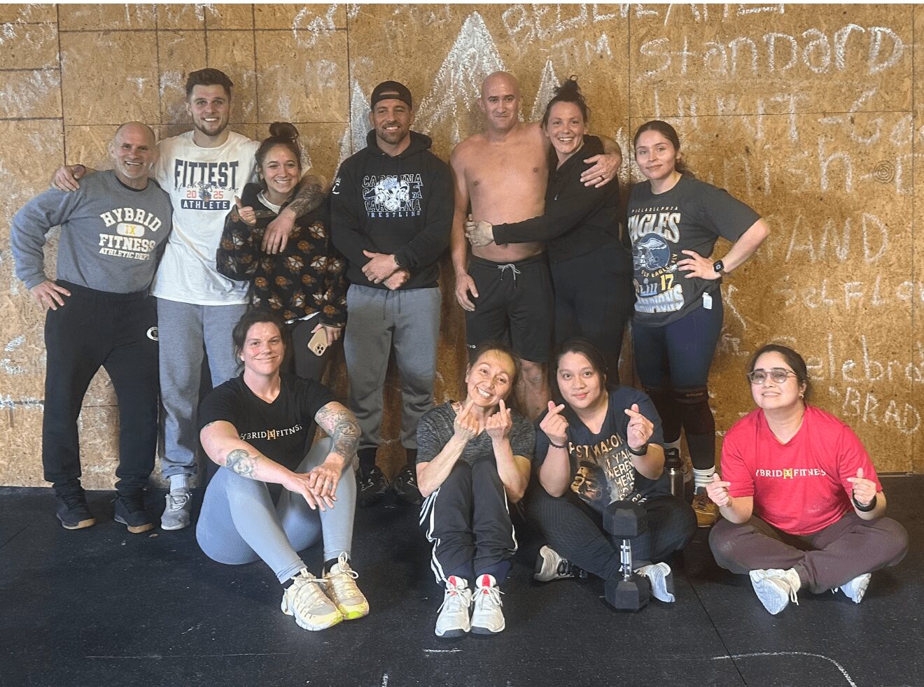 Group of ten people posing indoors, some standing and some sitting, with a graffiti-covered wall behind them.