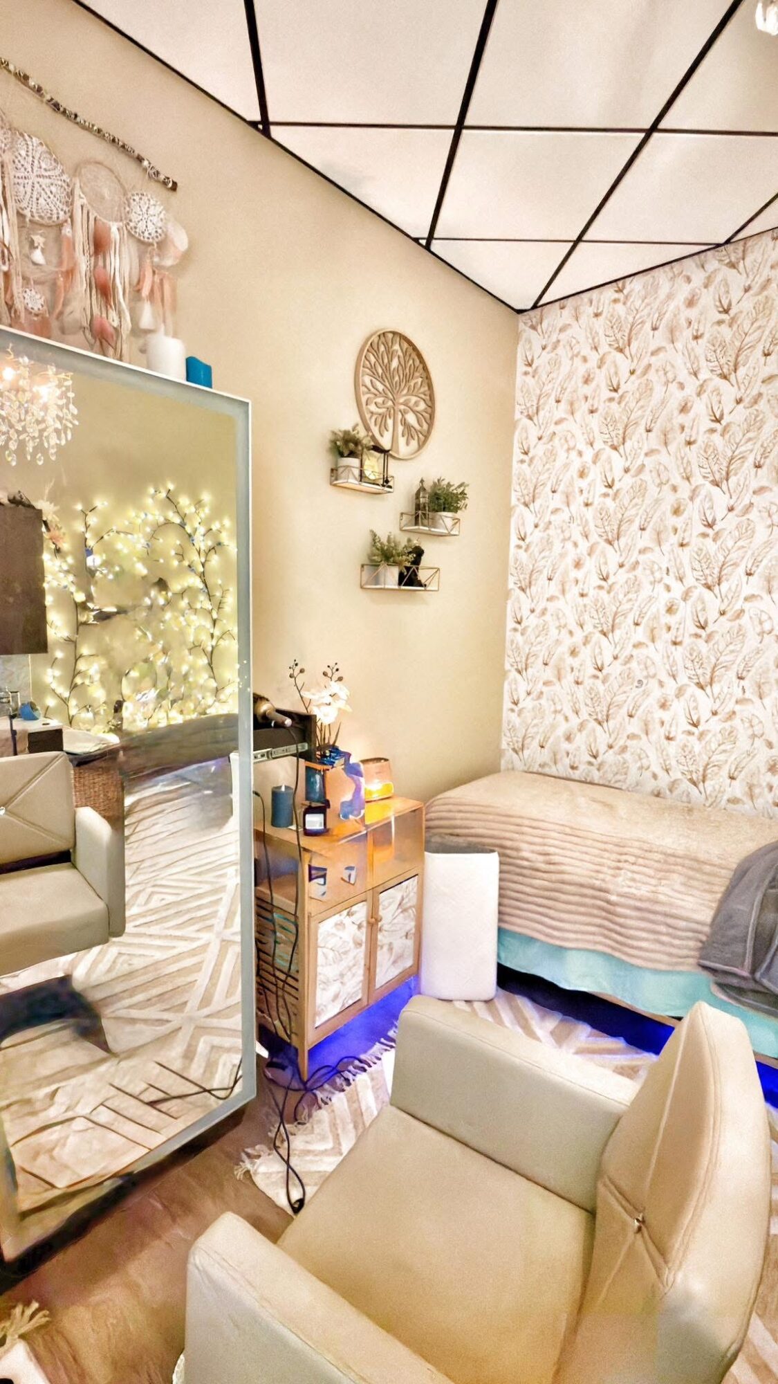 Room with a bed, mirror, wall decorations, and a chair, featuring a patterned wall and ceiling panels.