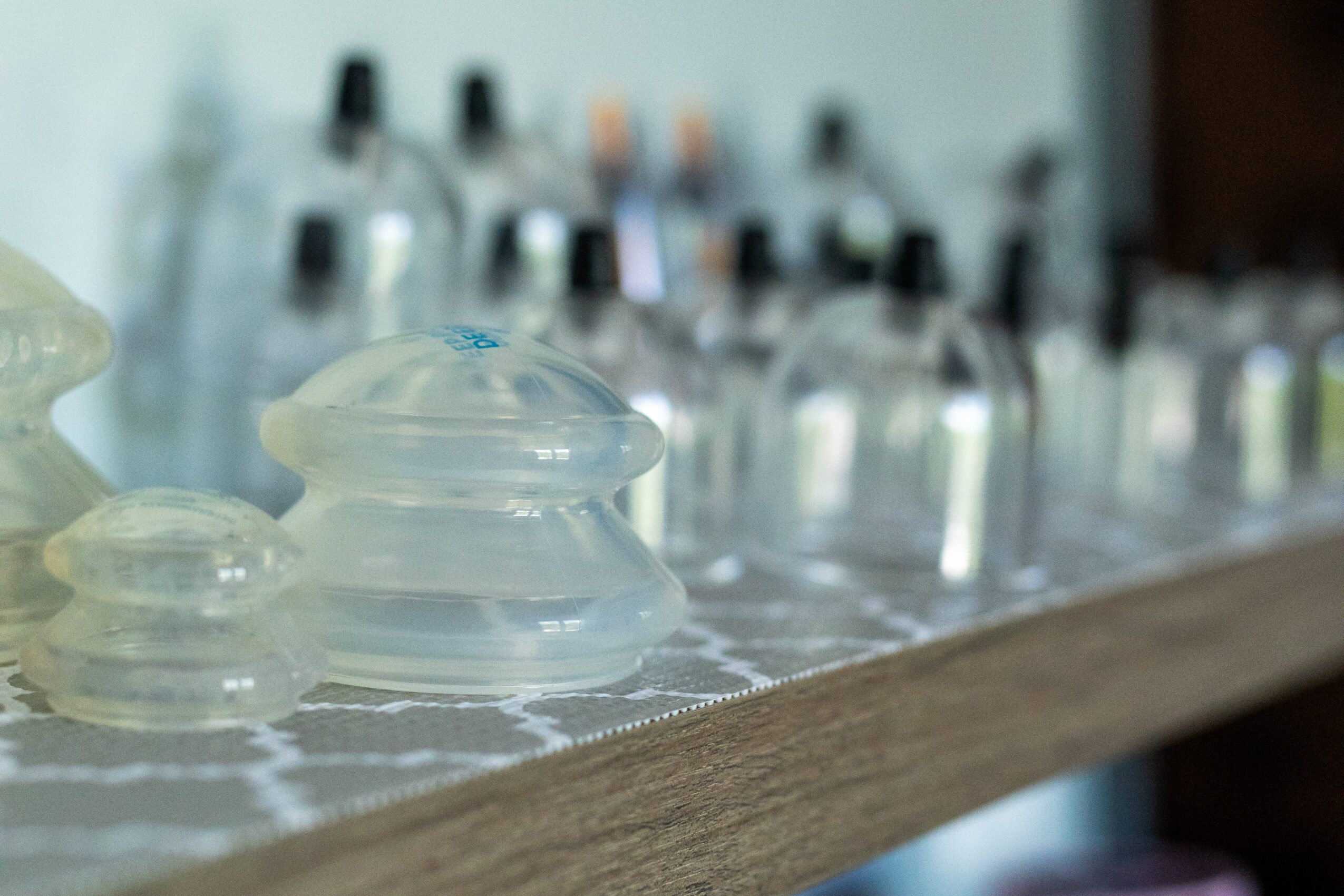 Close-up of glass domes on a wooden surface, with blurred bottles in the background.