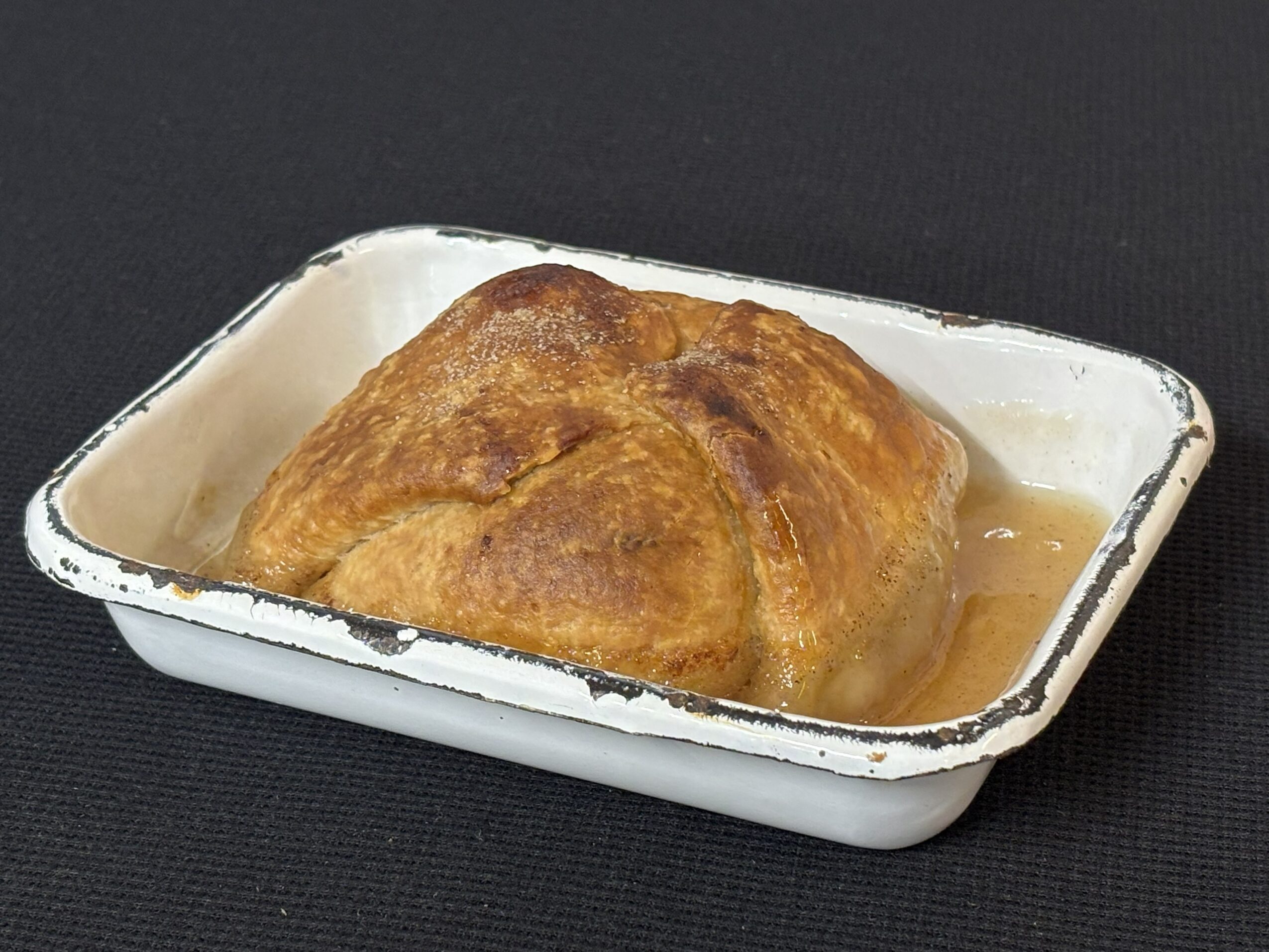 Baked dish with a golden-brown crust in a white rectangular baking dish, on a black surface.