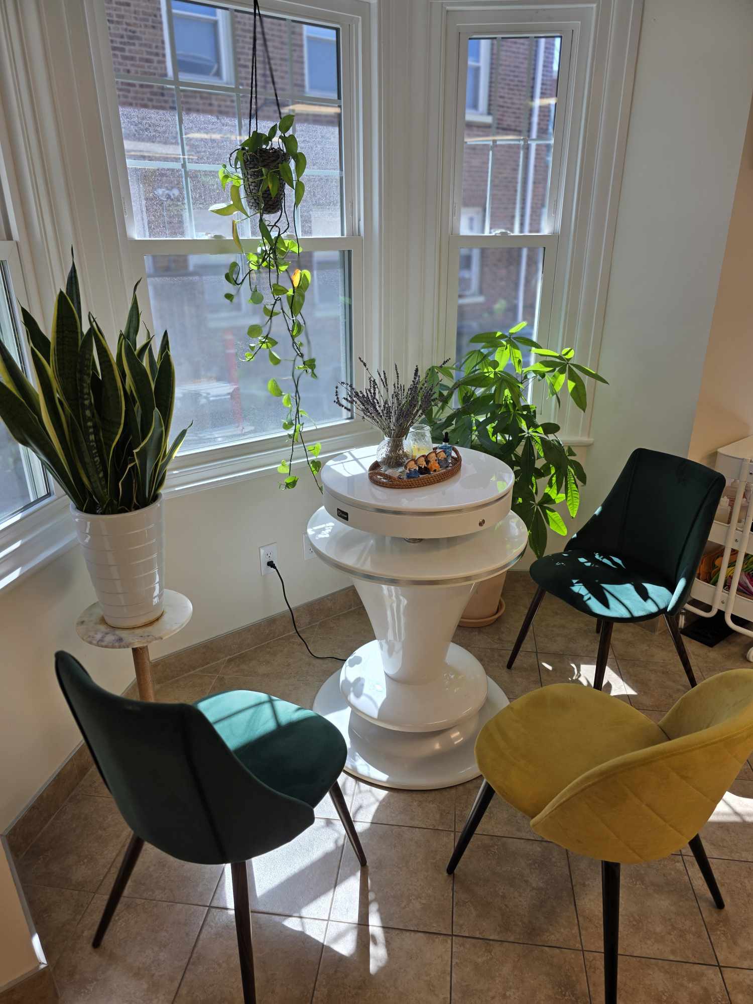 Corner with three chairs, a plant, and a window with sunlight, in a cozy indoor space.