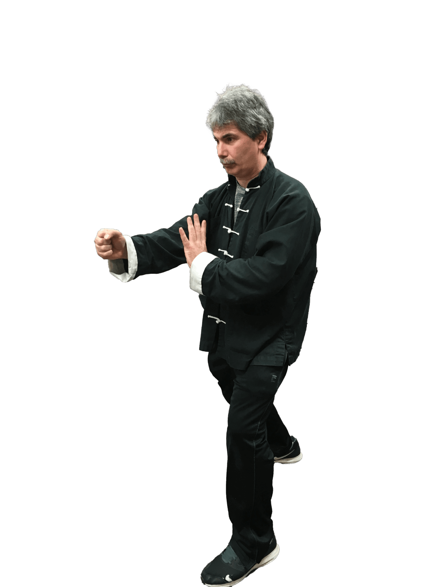 Person practicing martial arts stance with fists raised, wearing black traditional clothing, against a black background.