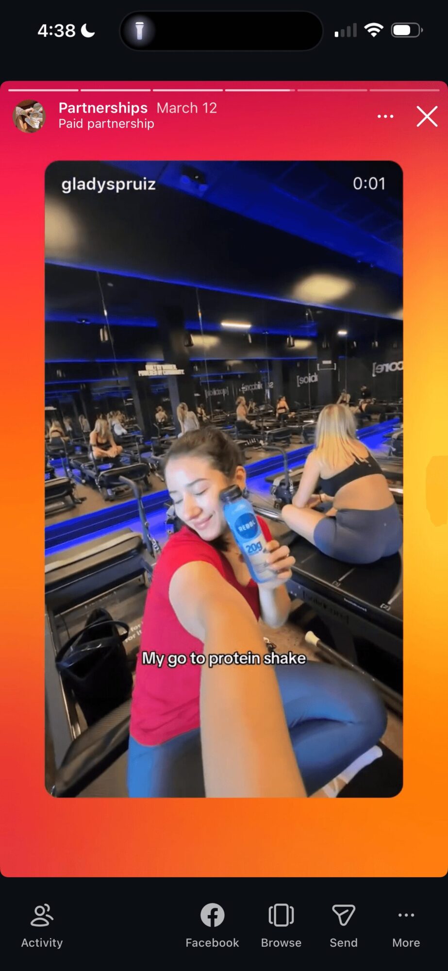 Person in red shirt smiling at camera, others in background at a restaurant or cafe, with blue lighting.