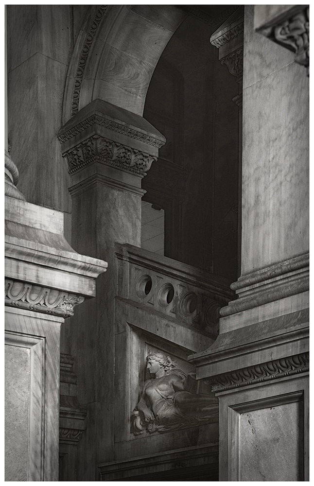 Architectural details of a classical building with columns, arches, and decorative stonework in black and white.