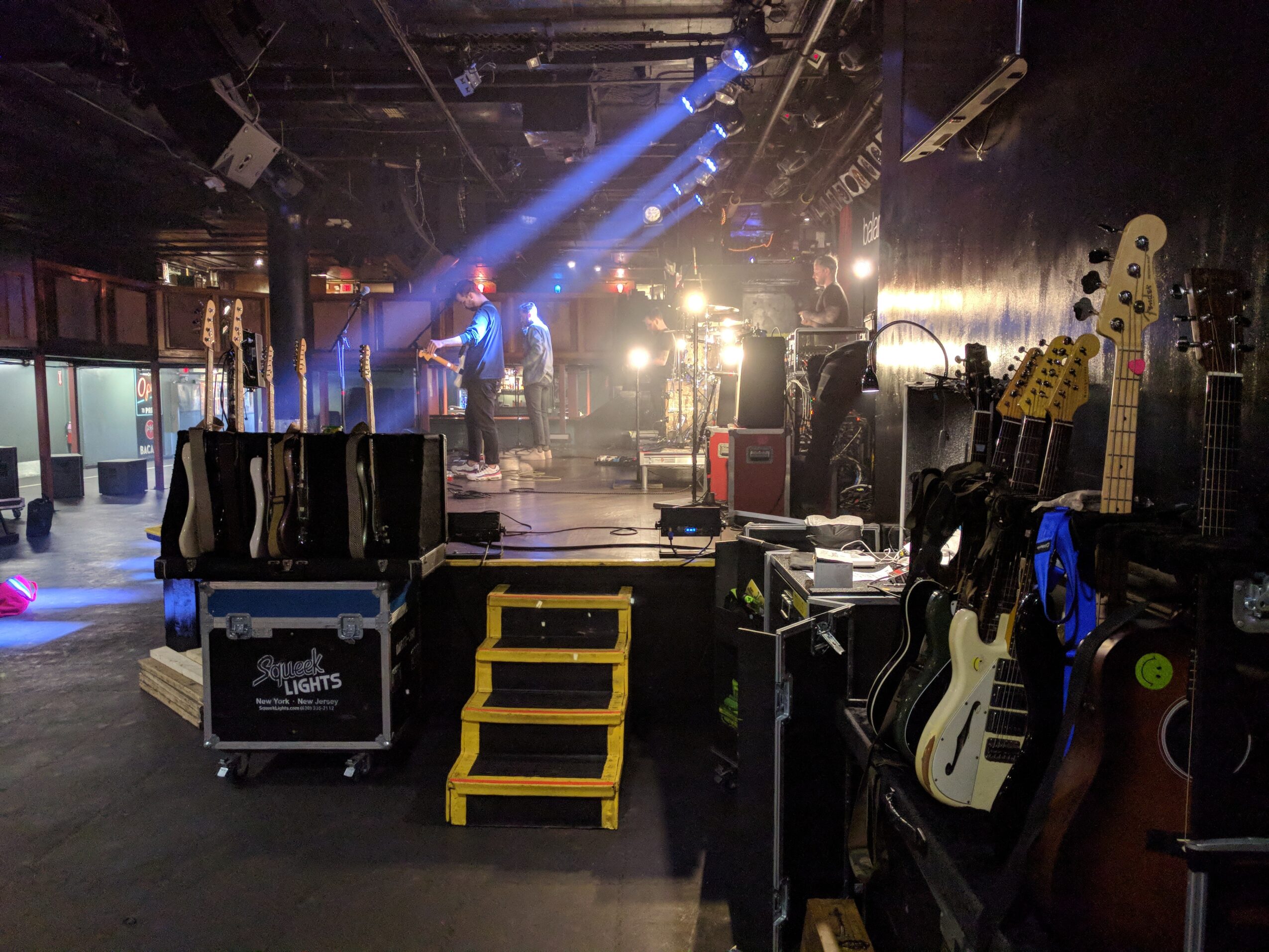 Stage with musical instruments and equipment, stage lights shining, and a dark venue interior.