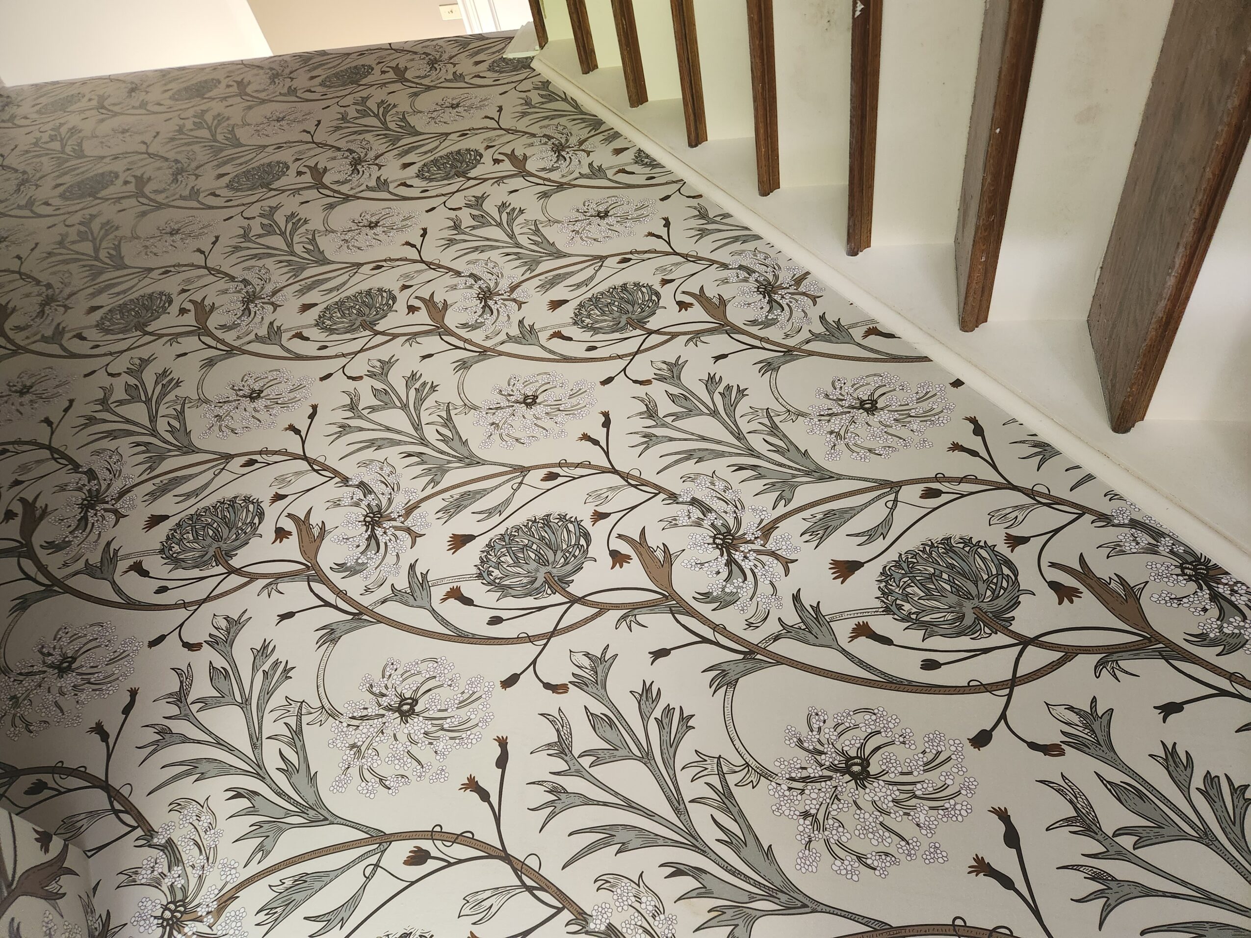 Carpet with floral pattern and wooden slats on wall, viewed from above.
