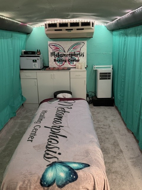 Room with teal curtains, a bed with a butterfly blanket, and a white cabinet with equipment, air conditioner, and a portable heater.
