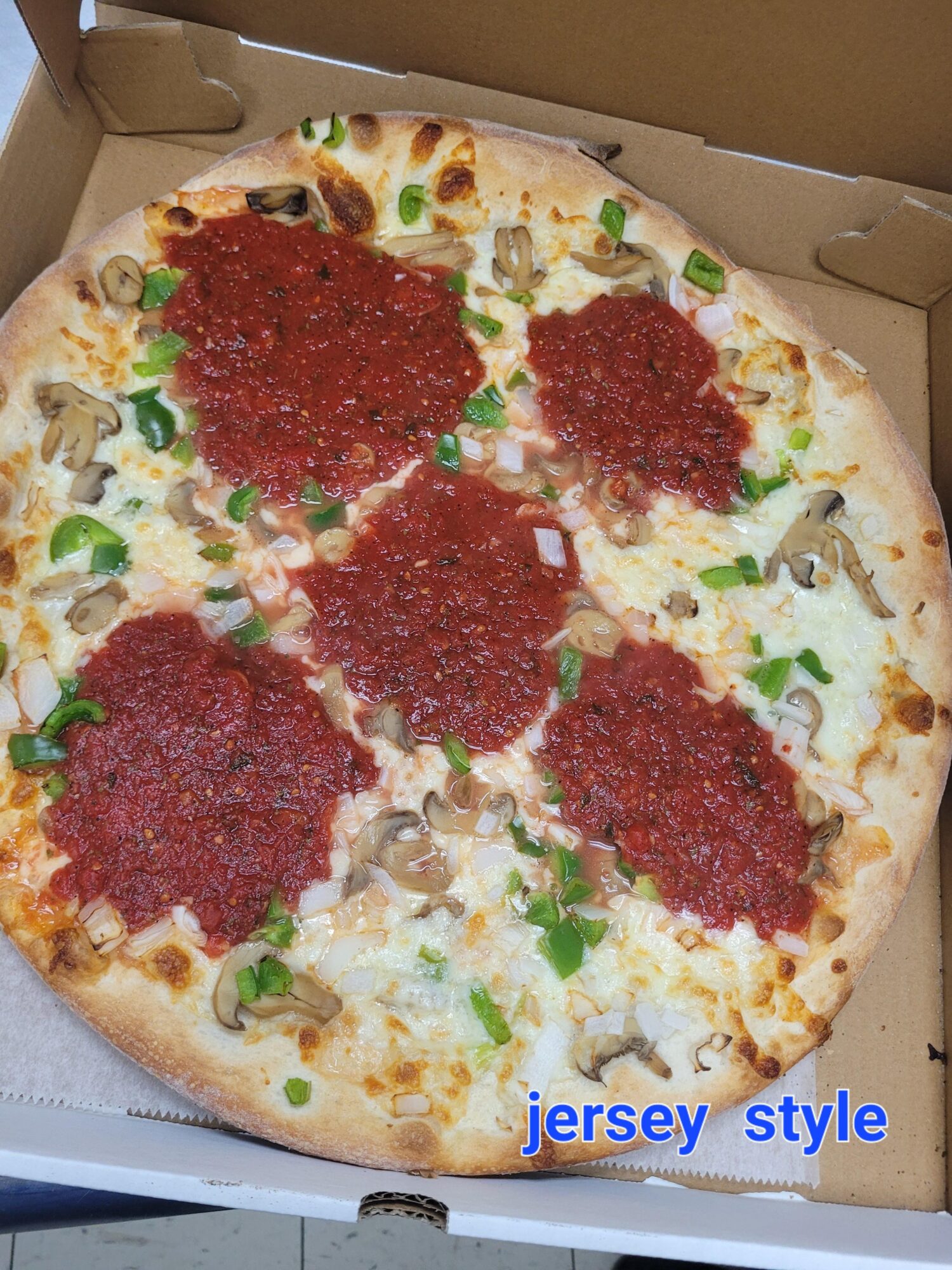 Pizza with pepperoni, green peppers, mushrooms, and cheese in a cardboard box.