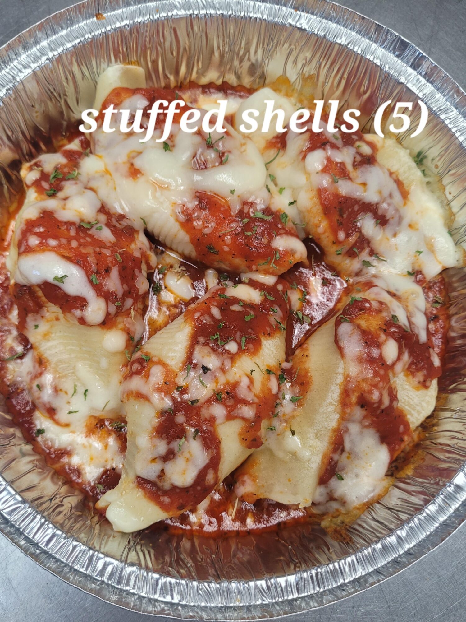 Aluminum container with five stuffed shells topped with tomato sauce and melted cheese, labeled 'stuffed shells (5)'.