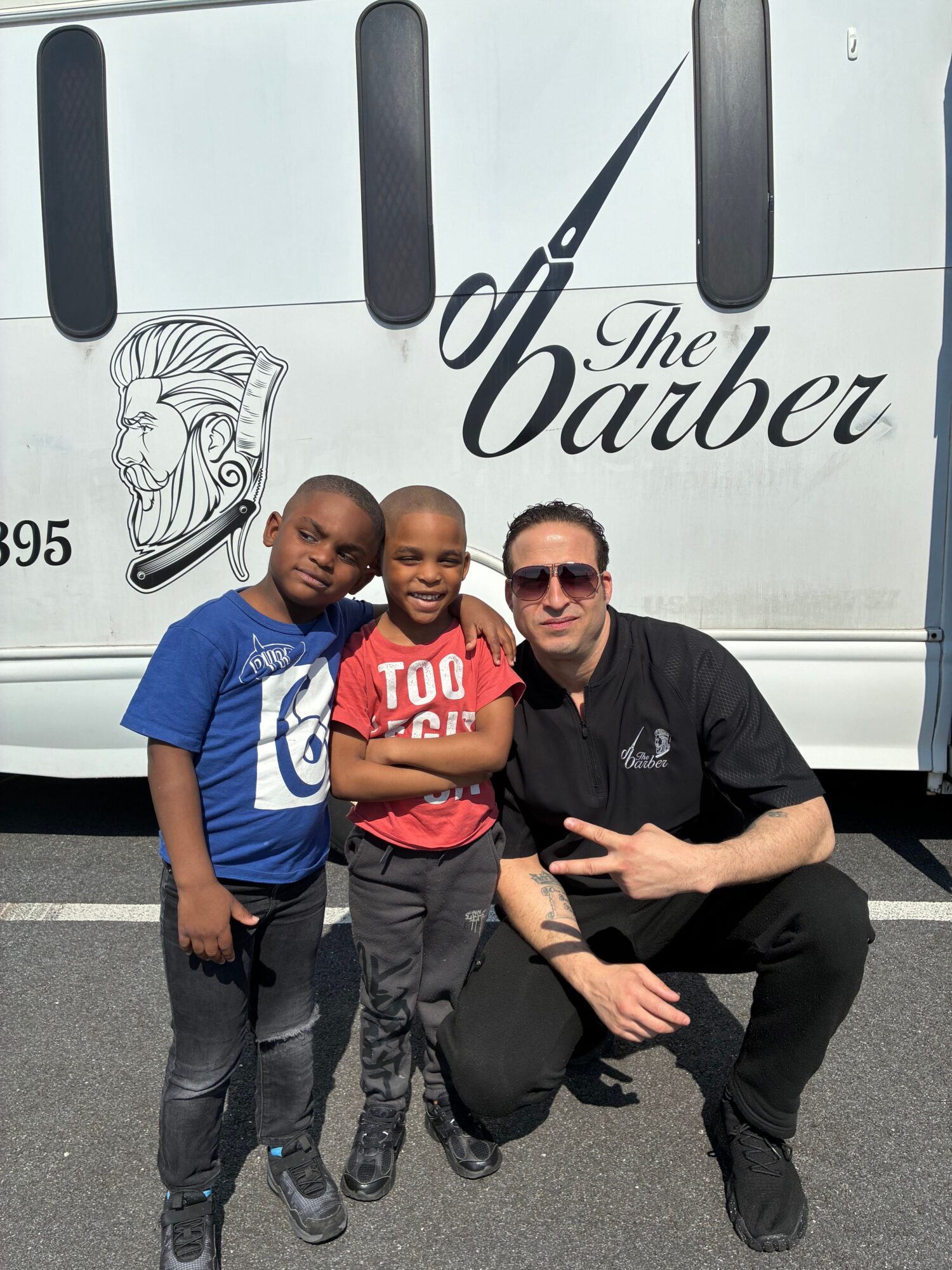 Three people posing in front of a van with the text 'The Dobber' and a logo, smiling and making gestures.