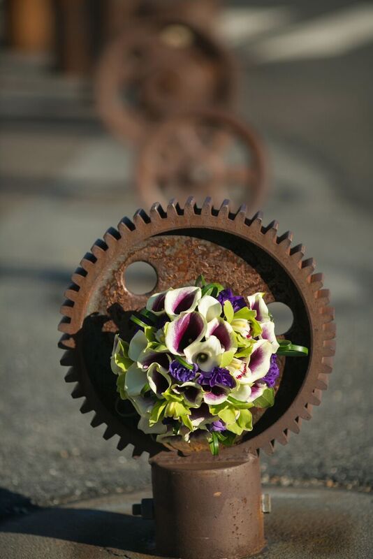 A bouquet of purple and white flowers inside a large gear with a rusty background.