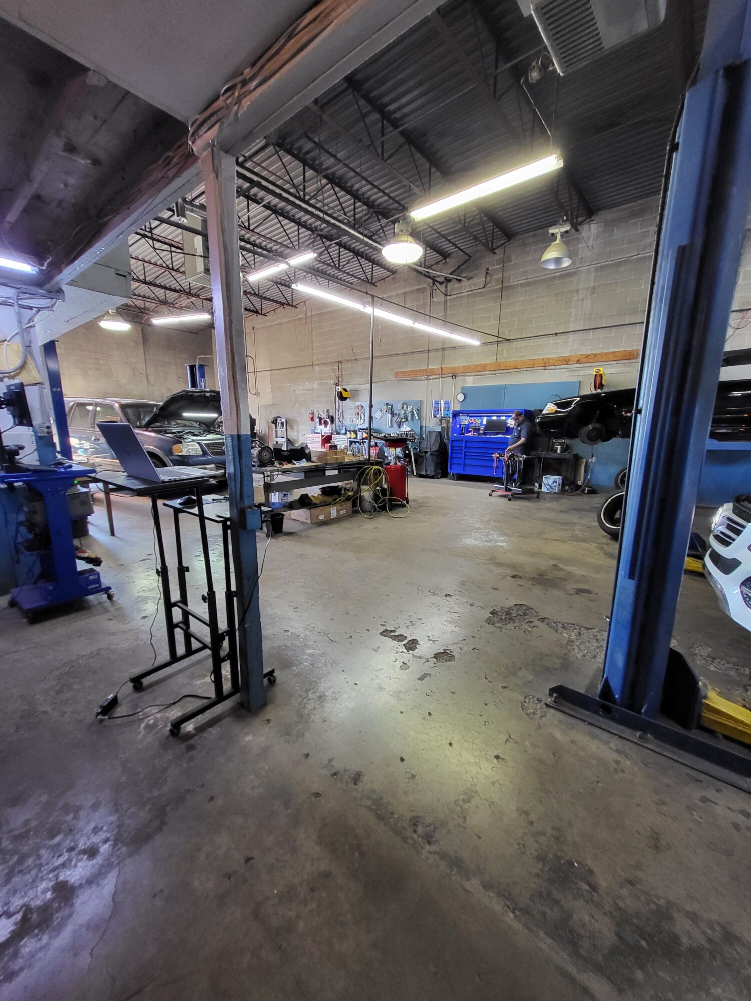 Industrial workshop with tools, equipment, and a blue container, viewed from a tilted angle.
