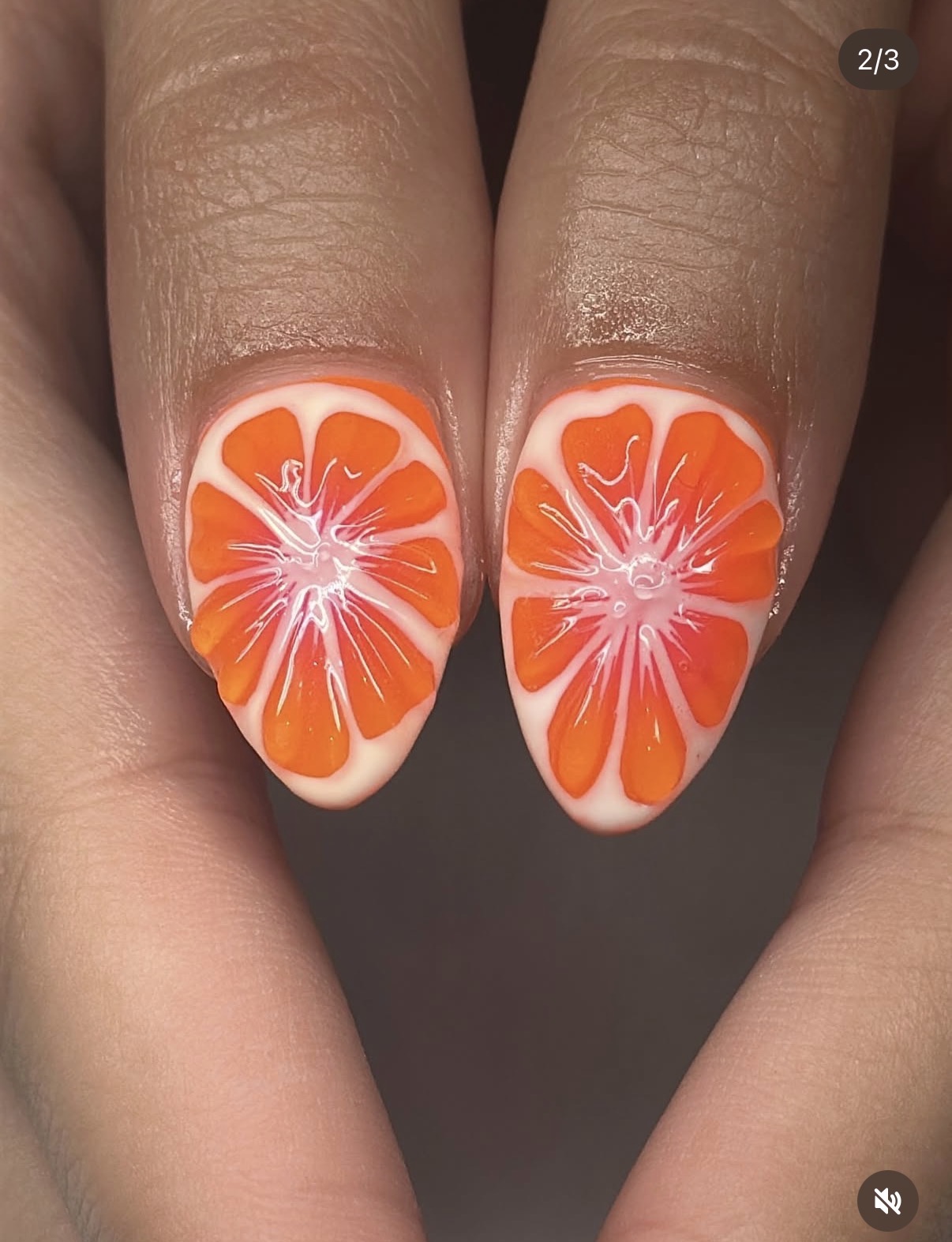Close-up of two fingernails with orange and white citrus slice nail art, detailed and vibrant.