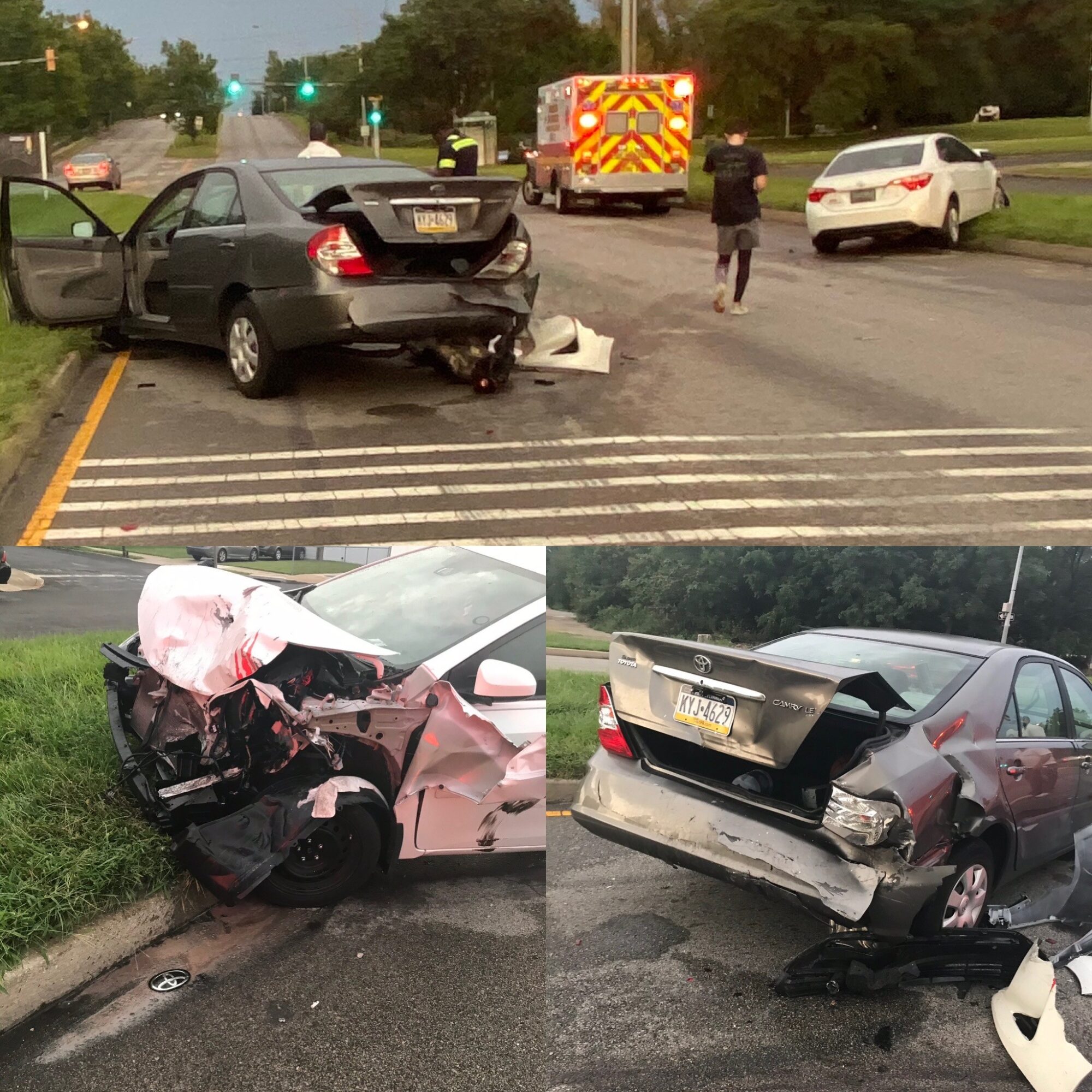 Two damaged cars involved in a collision, one on the road and one on the grass, with emergency vehicle and people nearby.