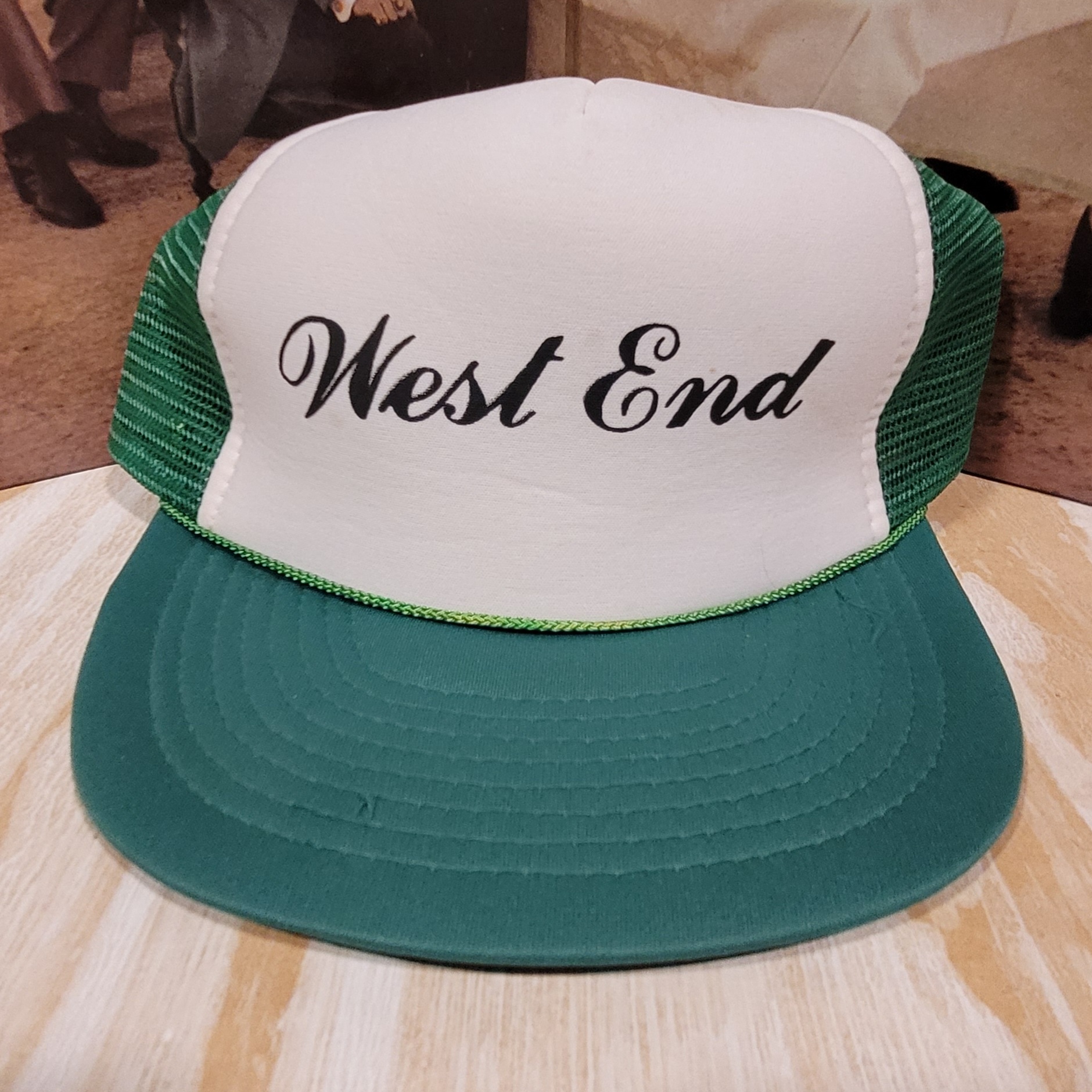 Cap with white front, green mesh sides, and teal brim, displaying 'West End' in black cursive text.