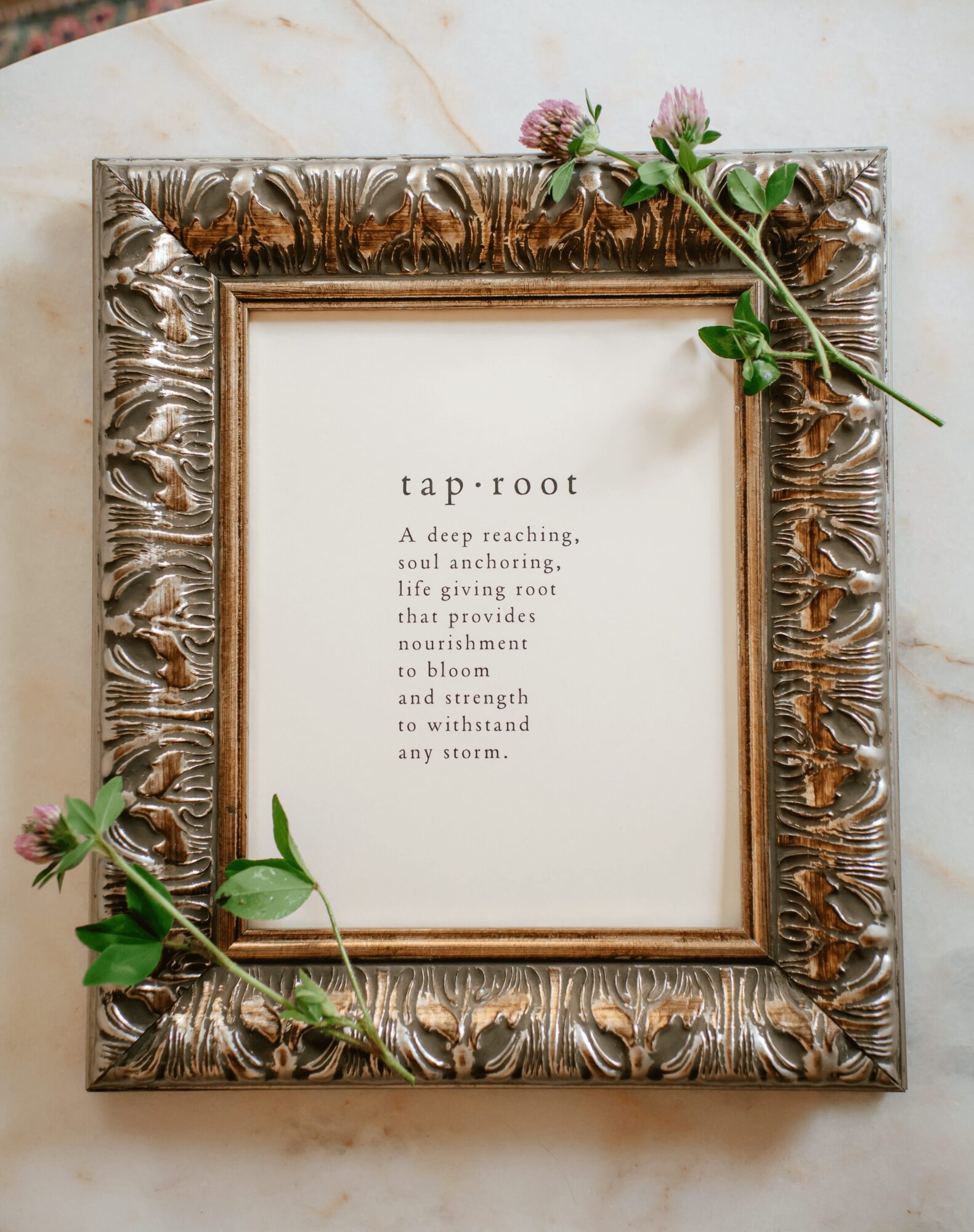 Decorative silver frame with a poem titled 'tap: root' and pink flowers on top and bottom corners.