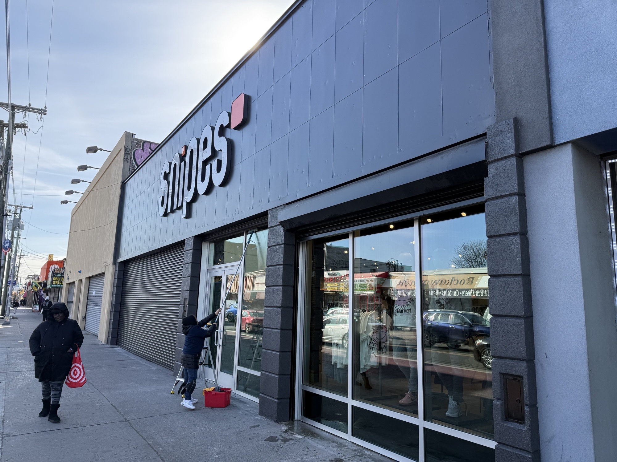 Exterior of a retail store with large glass windows and a sign reading 'supes' on a city sidewalk.