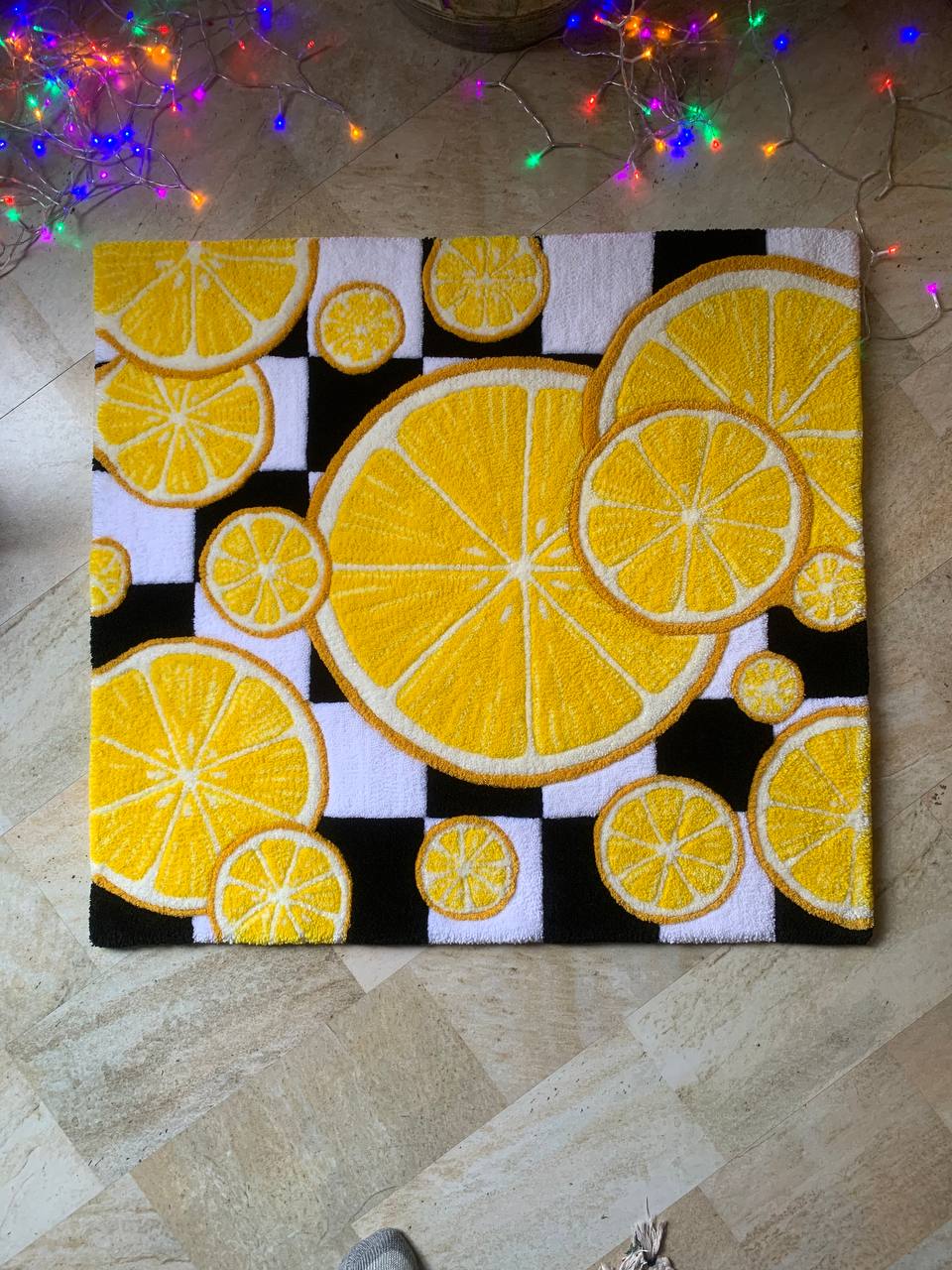 Painting of lemon slices in yellow, black, and white, arranged in a pattern on a square canvas.