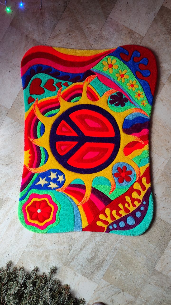 Colorful rug with peace sign, flowers, and abstract patterns, placed on a tiled floor.