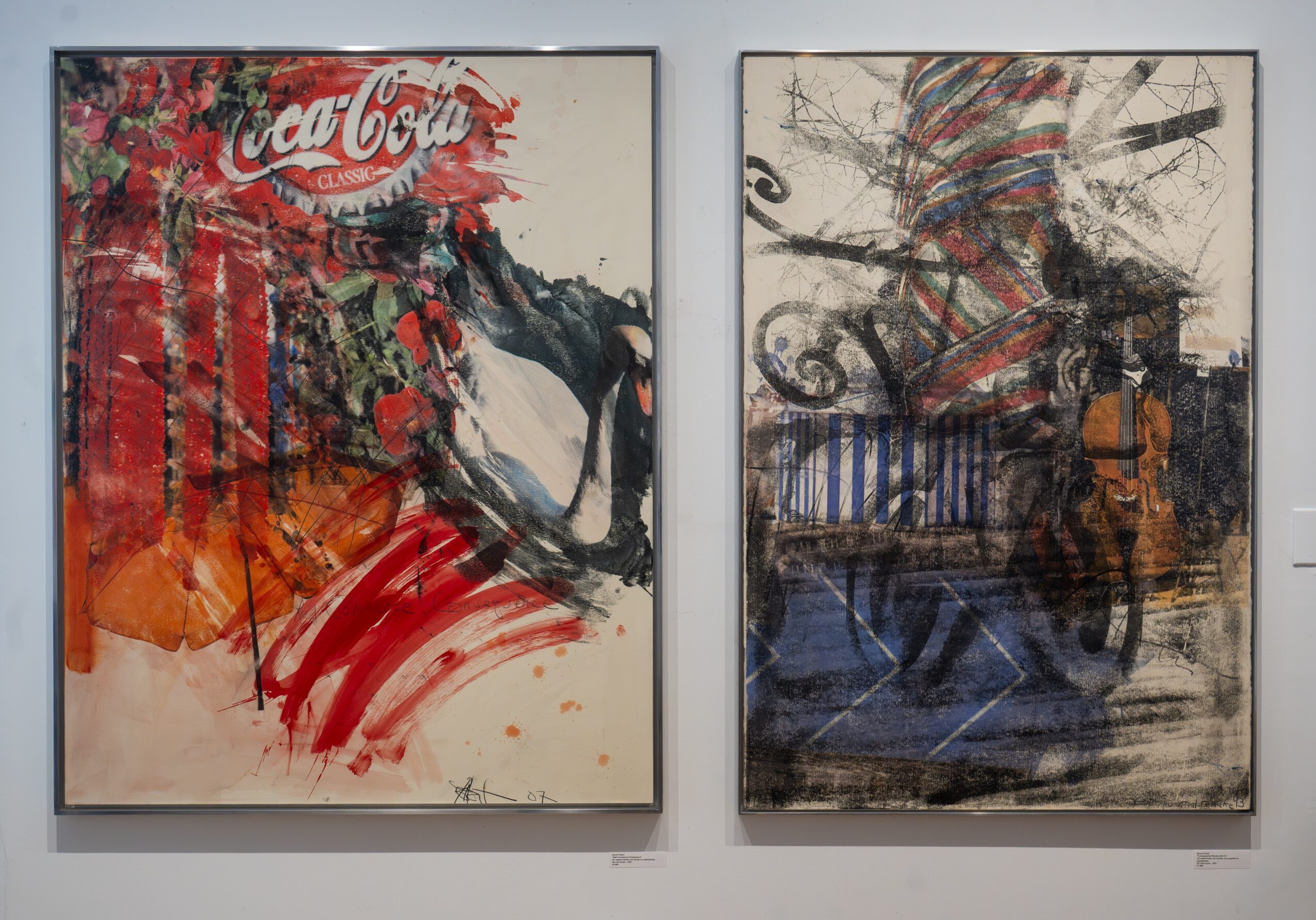 Two abstract paintings on a wall, one with red and black colors and a Coca-Cola logo, the other with dark and muted tones.