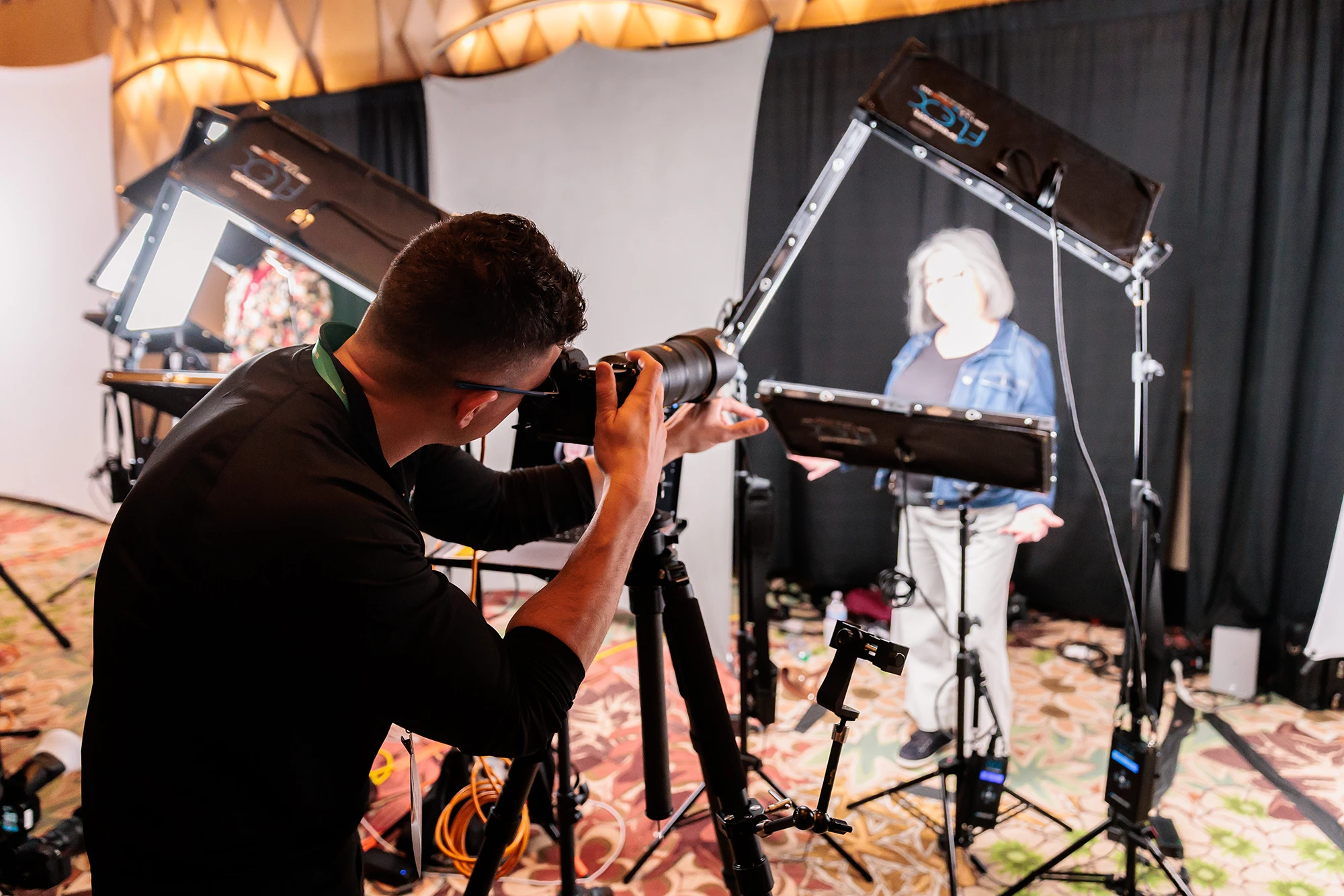 Photographer taking a picture of a woman on stage with professional lighting and camera equipment.