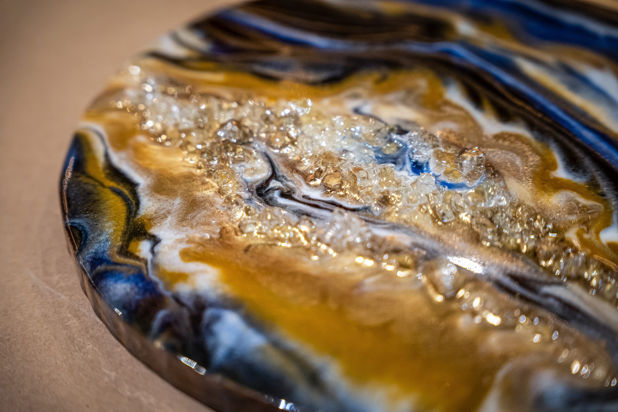 Close-up of a polished, colorful stone with gold, black, white, and blue patterns and embedded crystals.