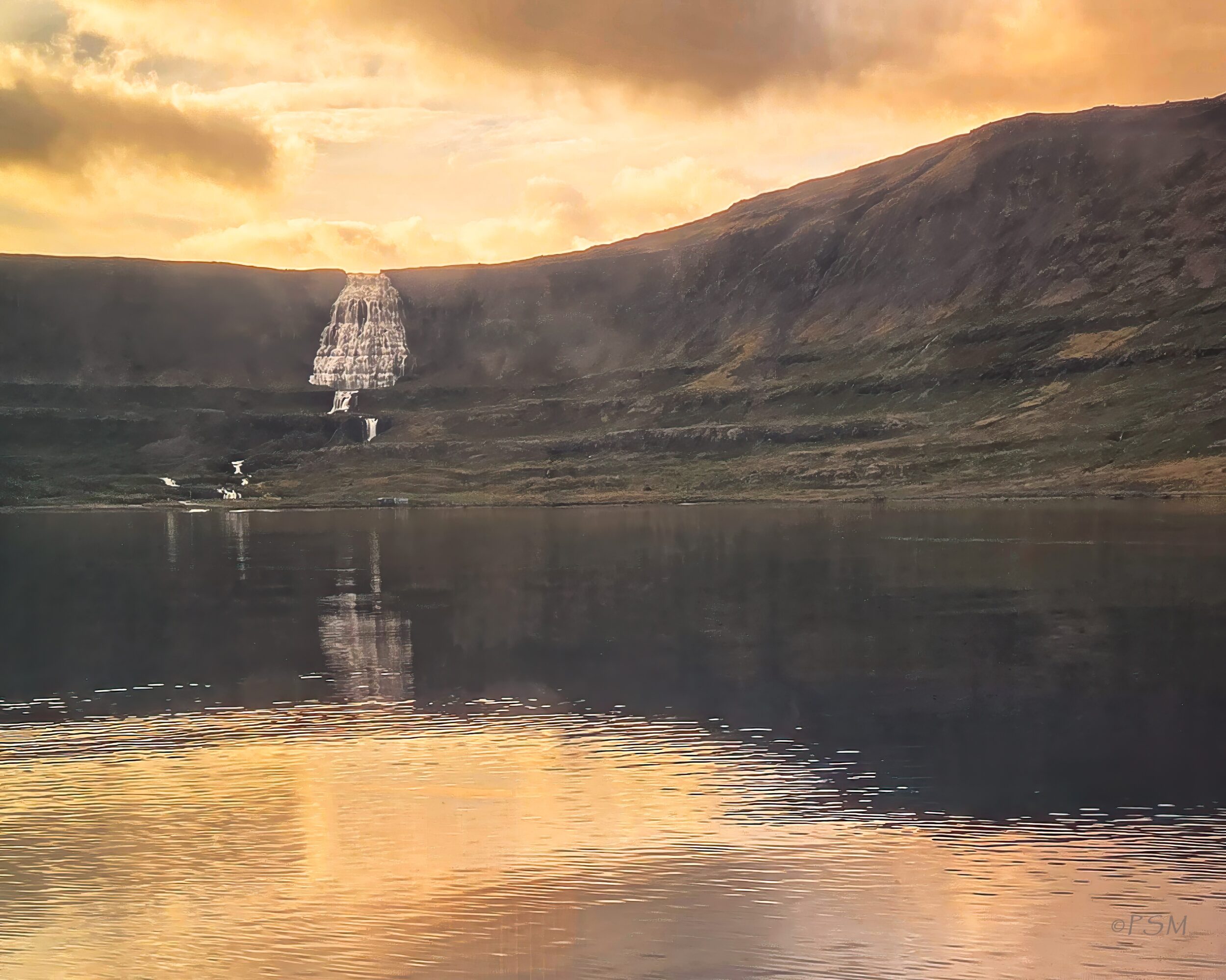 Sunset over a mountain with a waterfall, reflected in a lake, with warm sky colors and calm water surface.