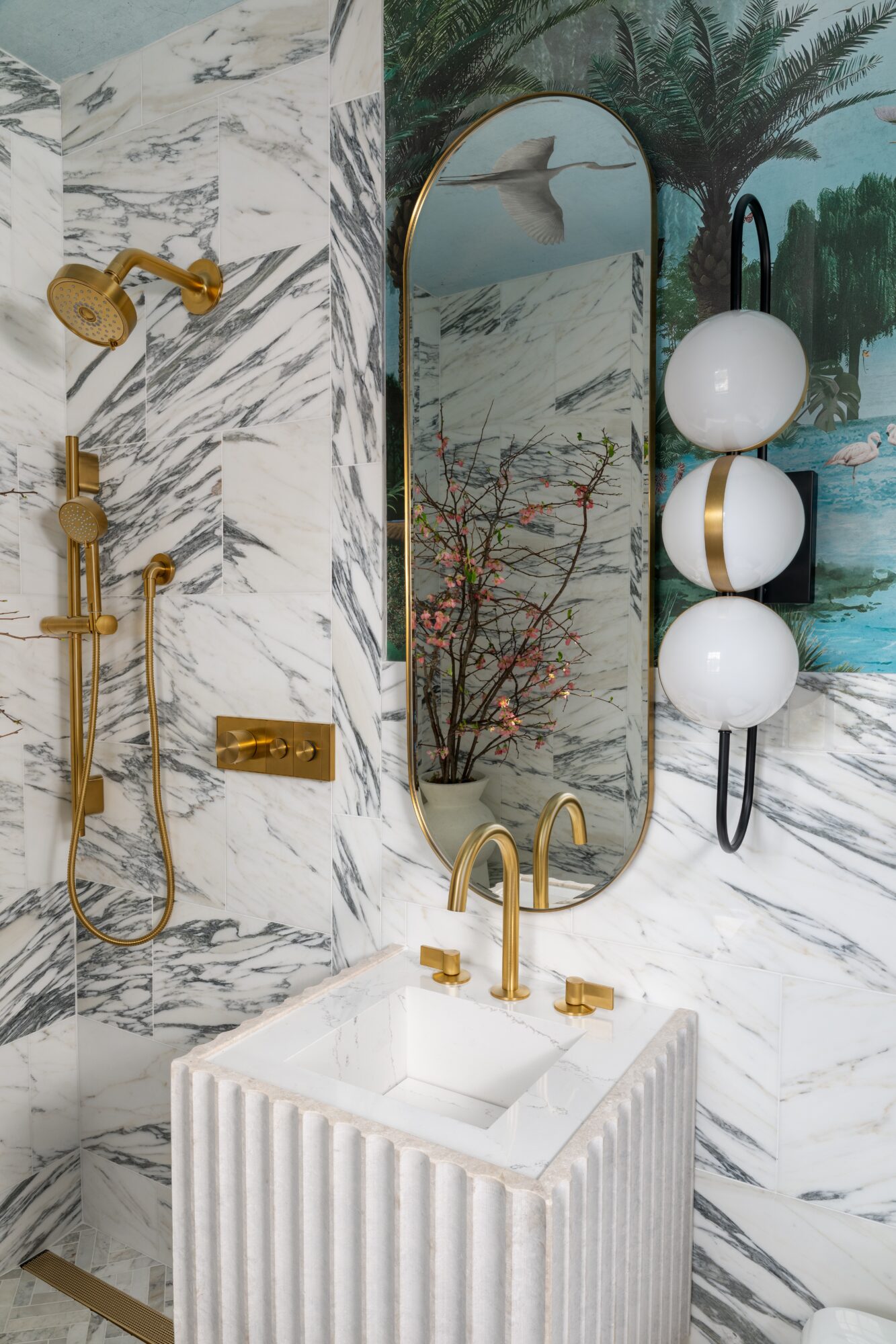 Bathroom with marble walls, gold fixtures, a mirror, and decorative white spherical lights.
