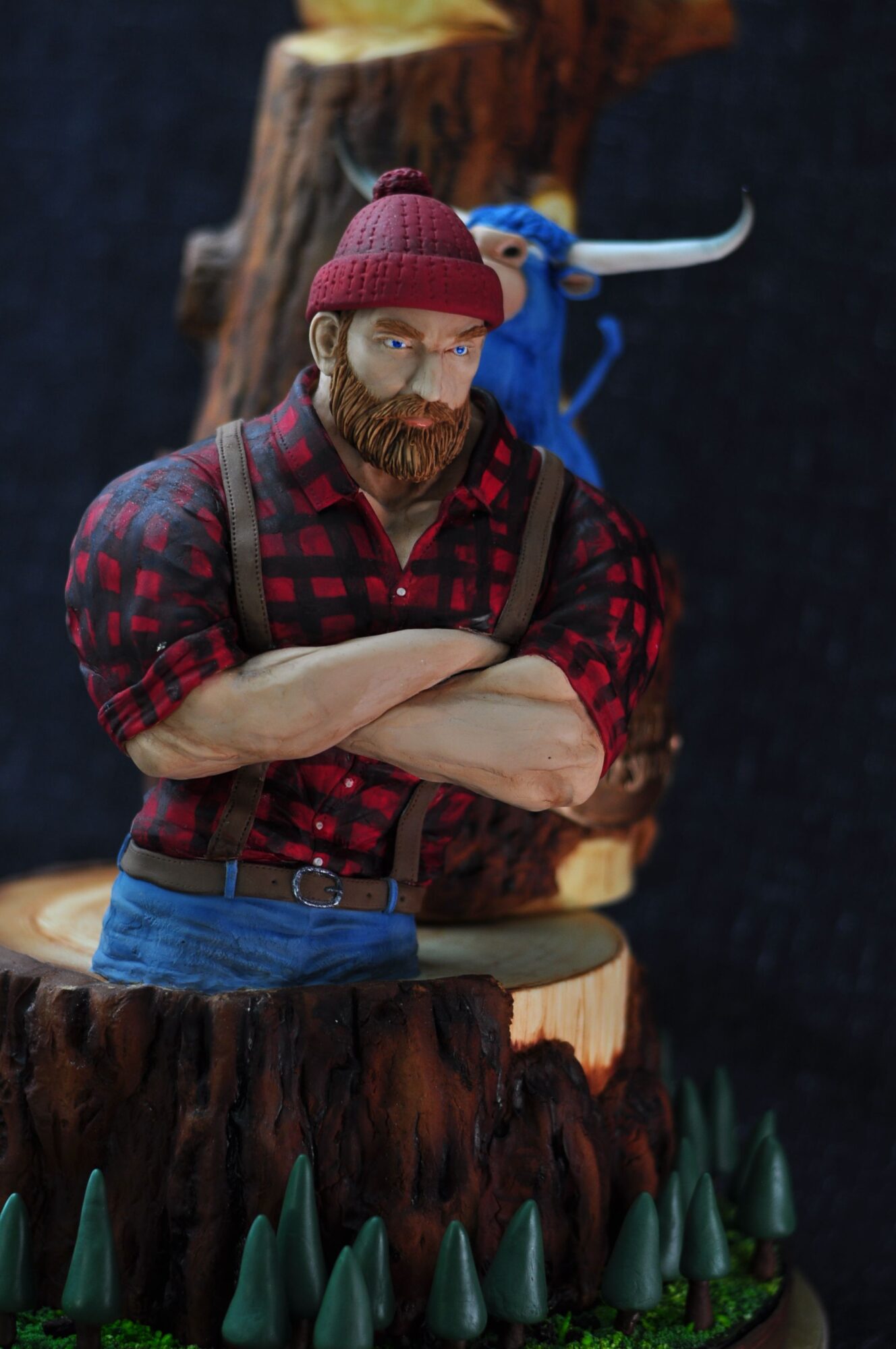 Person sitting on a log, wearing a red plaid shirt, pink hat, and glasses, with a backpack, outdoors.