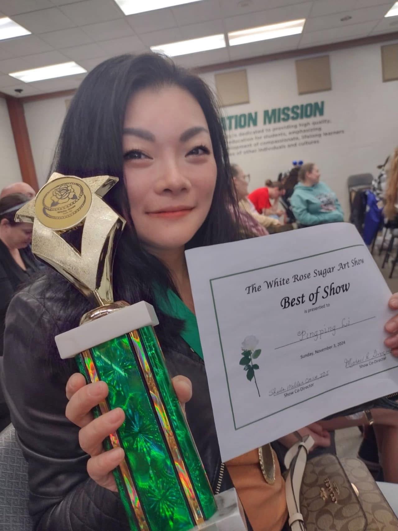 Woman holding a trophy and a certificate at an indoor event, smiling at the camera.