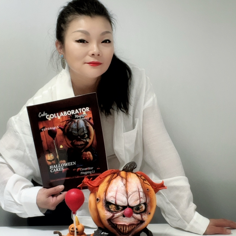 Woman with dark hair in a white jacket holding a Halloween-themed magazine, next to a pumpkin with a scary face.