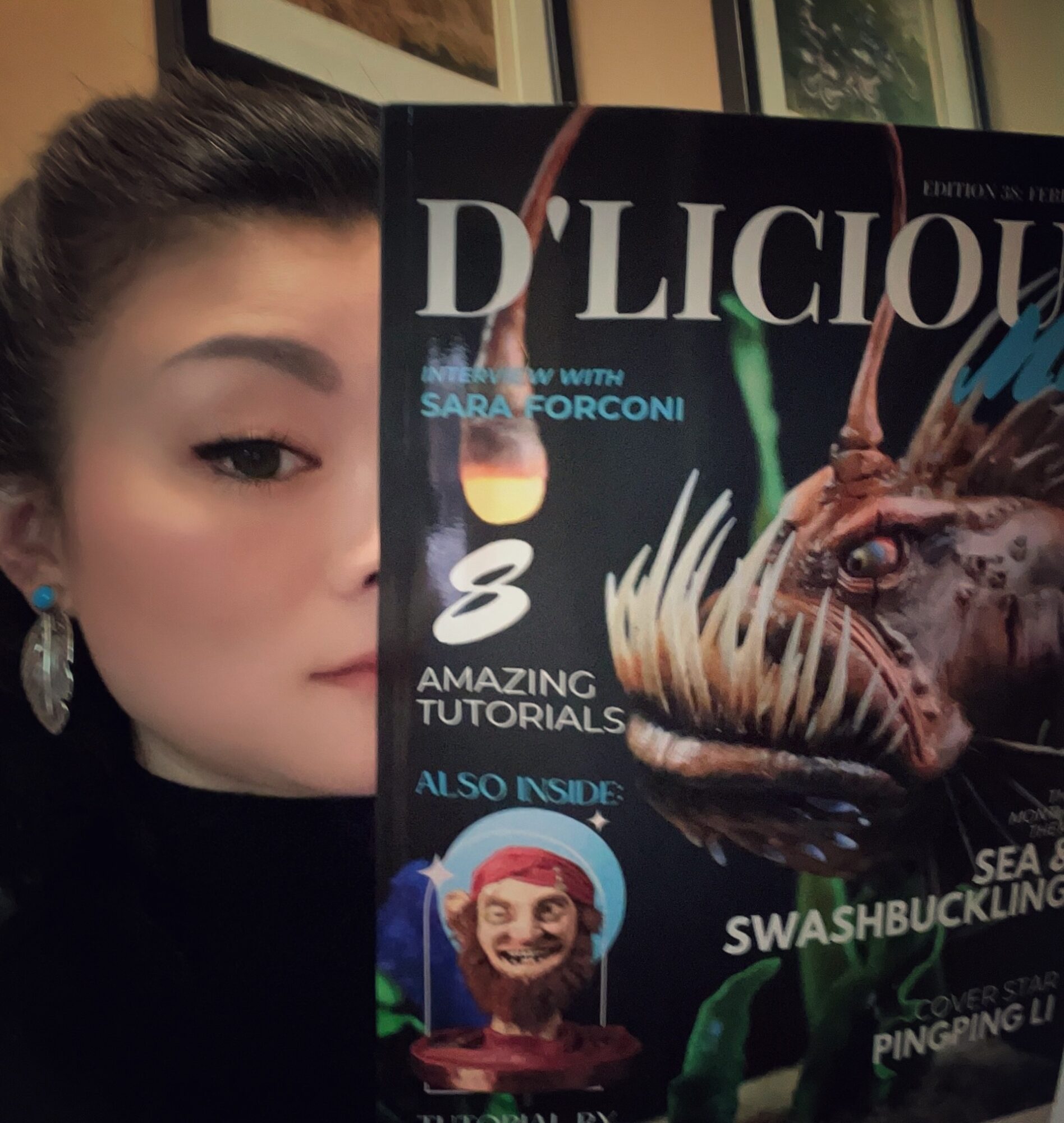Partially visible woman with dark hair and earrings holding a magazine with a creature on the cover.