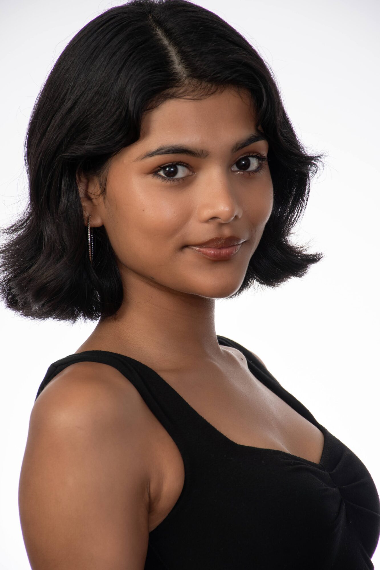Young woman with shoulder-length black hair, wearing a black top, looking at the camera with a neutral expression.