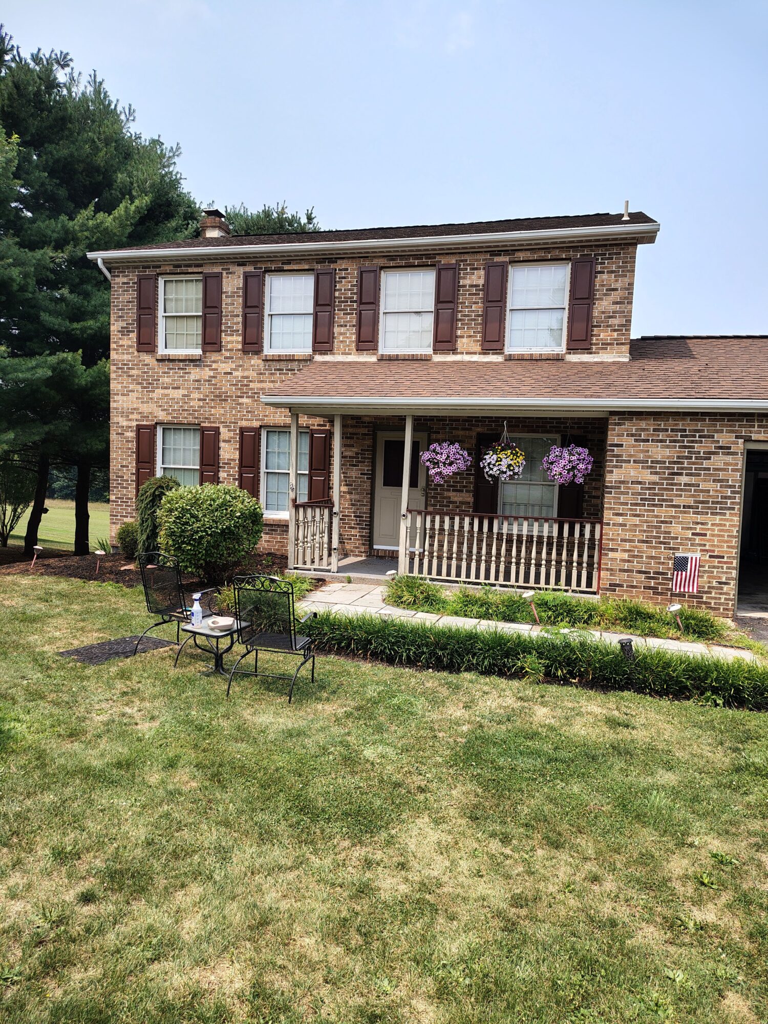 Three-story brick building with large windows, a small garden with purple flowers, and a lawn in front.