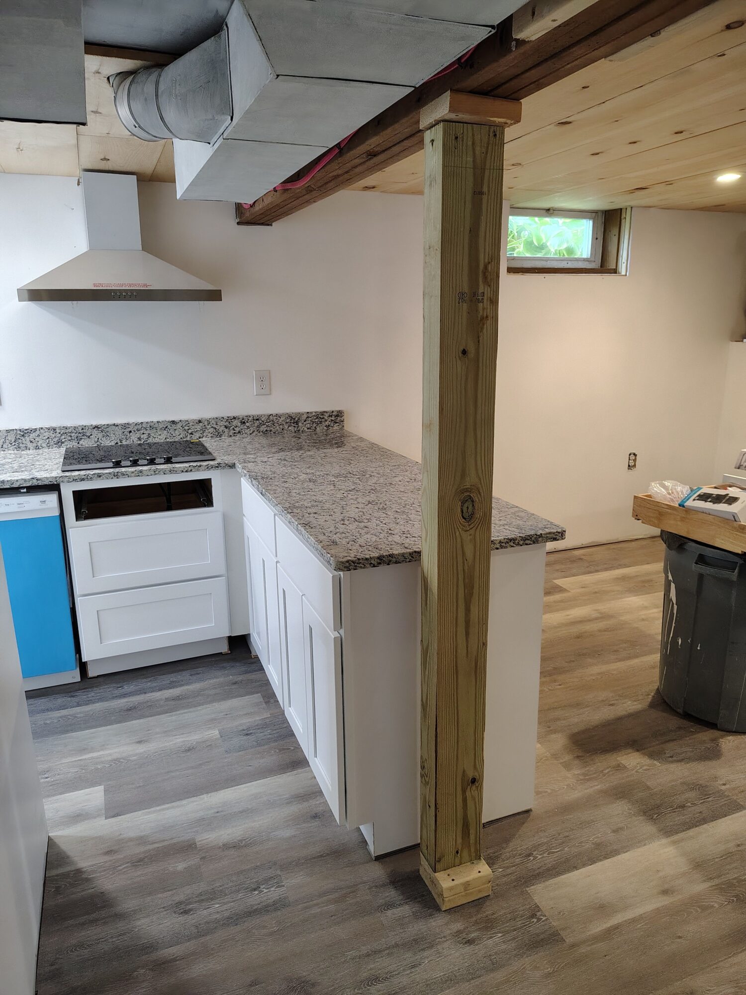 Interior view of a room with a wooden post, kitchen cabinets, and a window, rotated to the right.